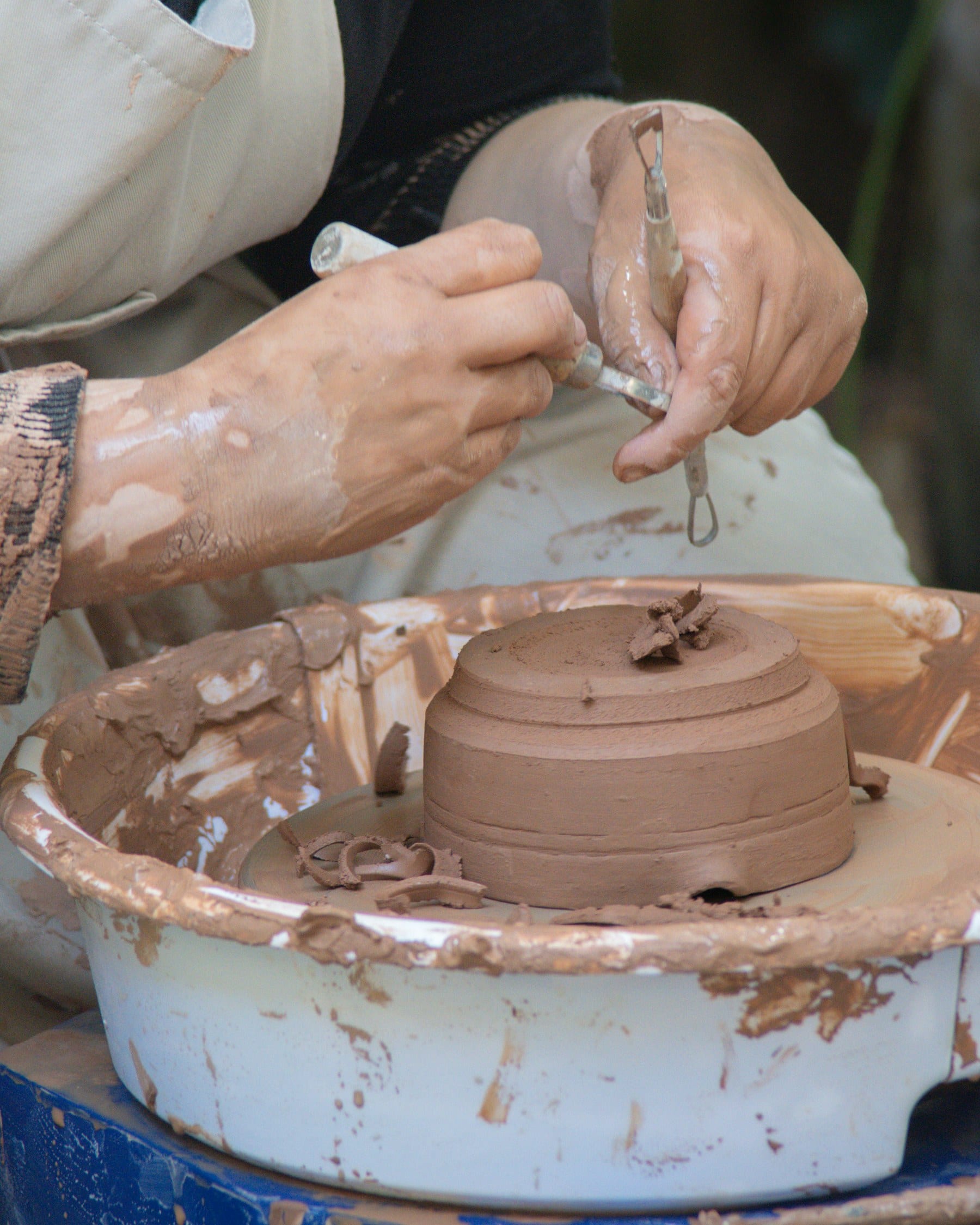 Hands smoothing the seam of a hand-built cylindrical vessel