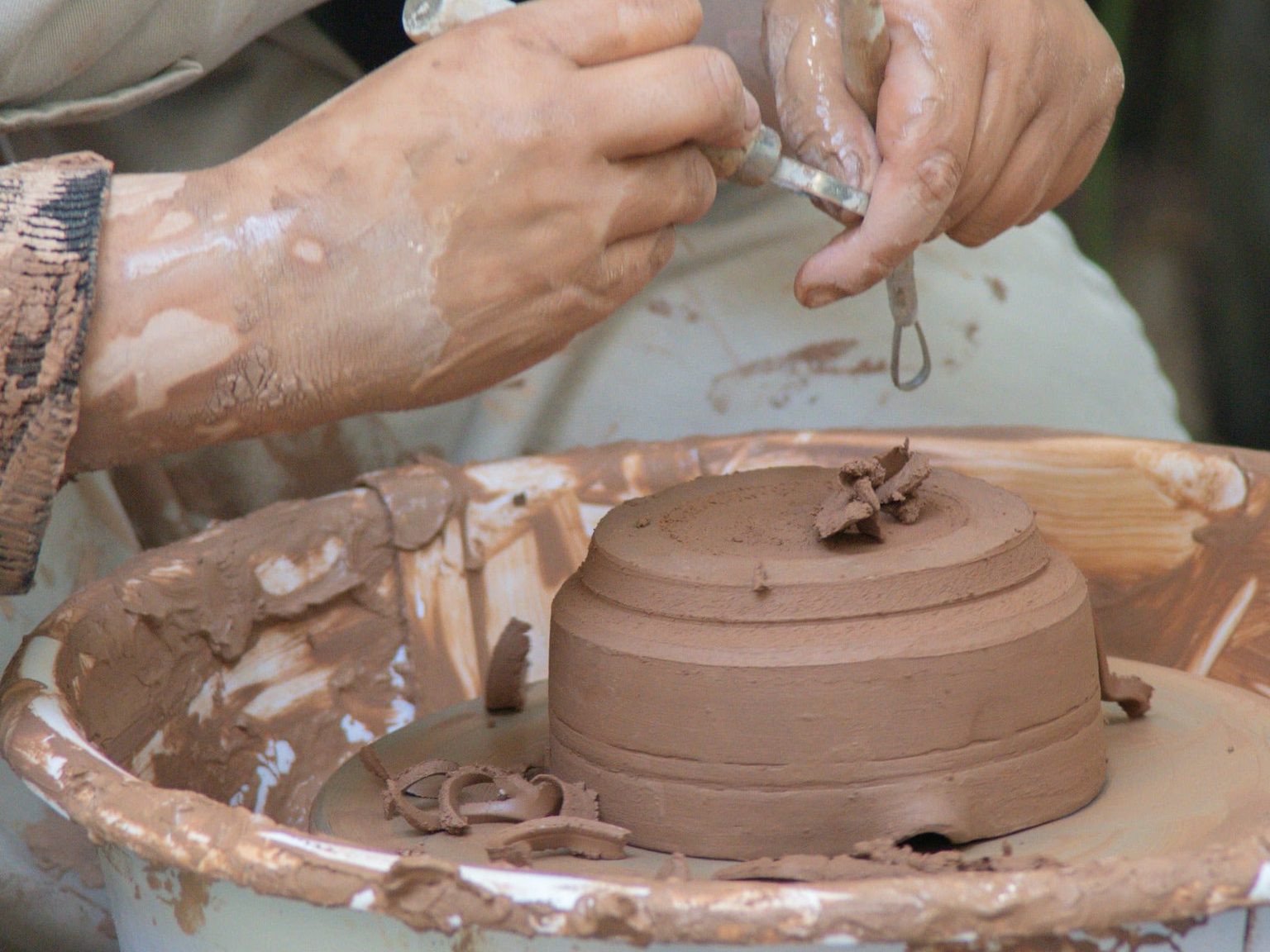 Hands smoothing the seam of a hand-built cylindrical vessel