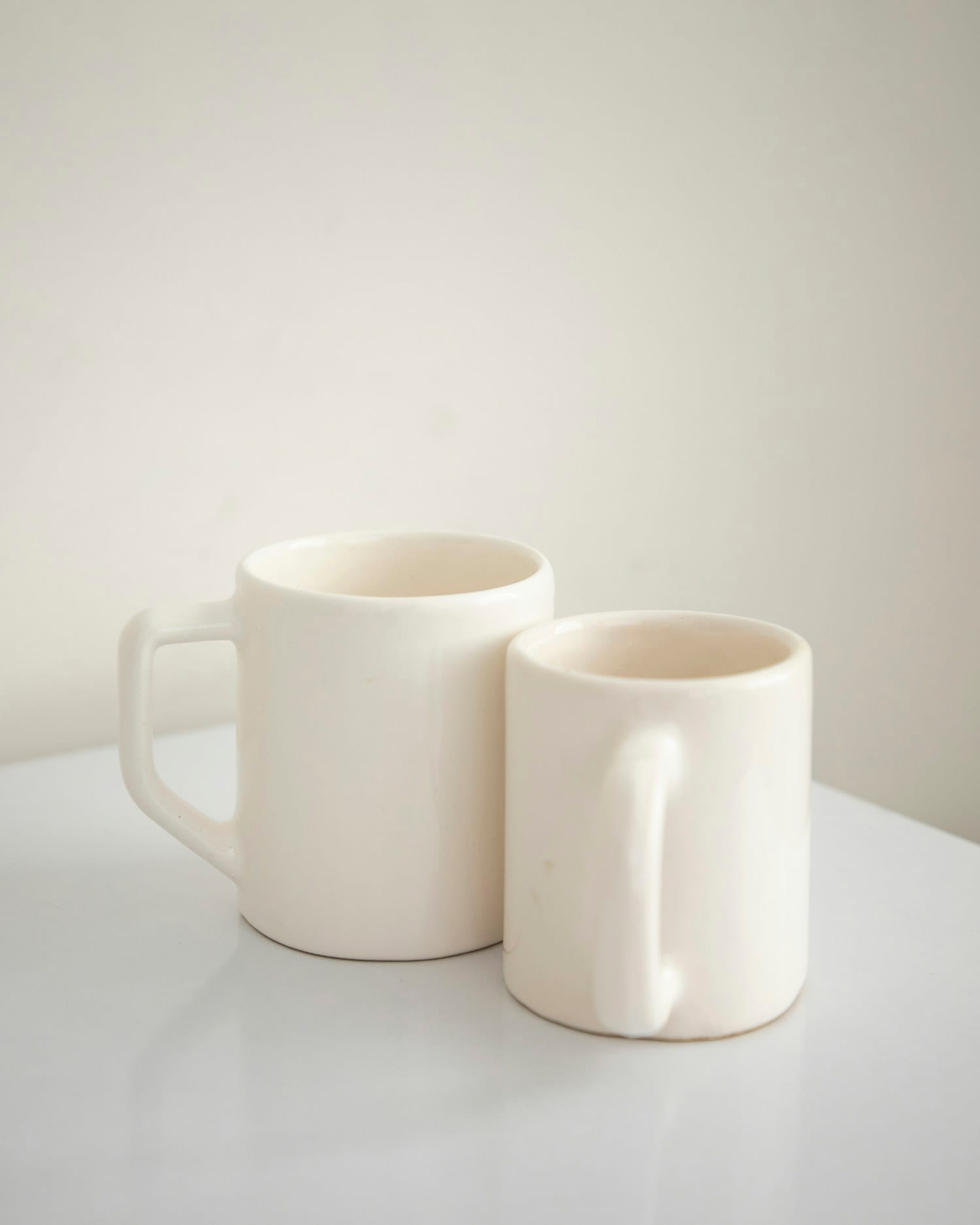 A pair of matte white mugs standing side by side
