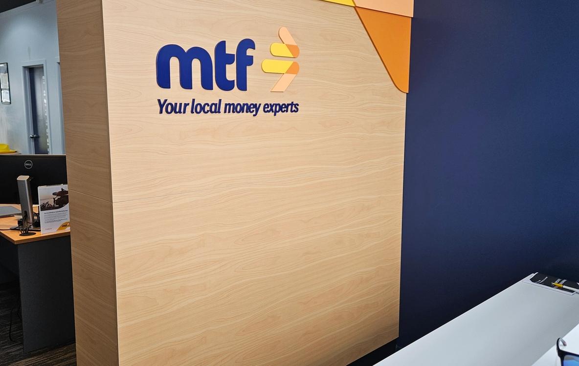 MTF Henderson reception with 3D acrylic logo and tagline on light-wood-veneer feature wall
