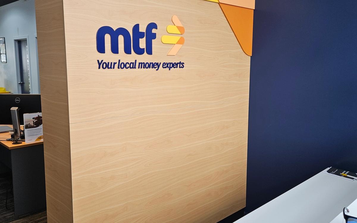 MTF Henderson reception with 3D acrylic logo and tagline on light-wood-veneer feature wall