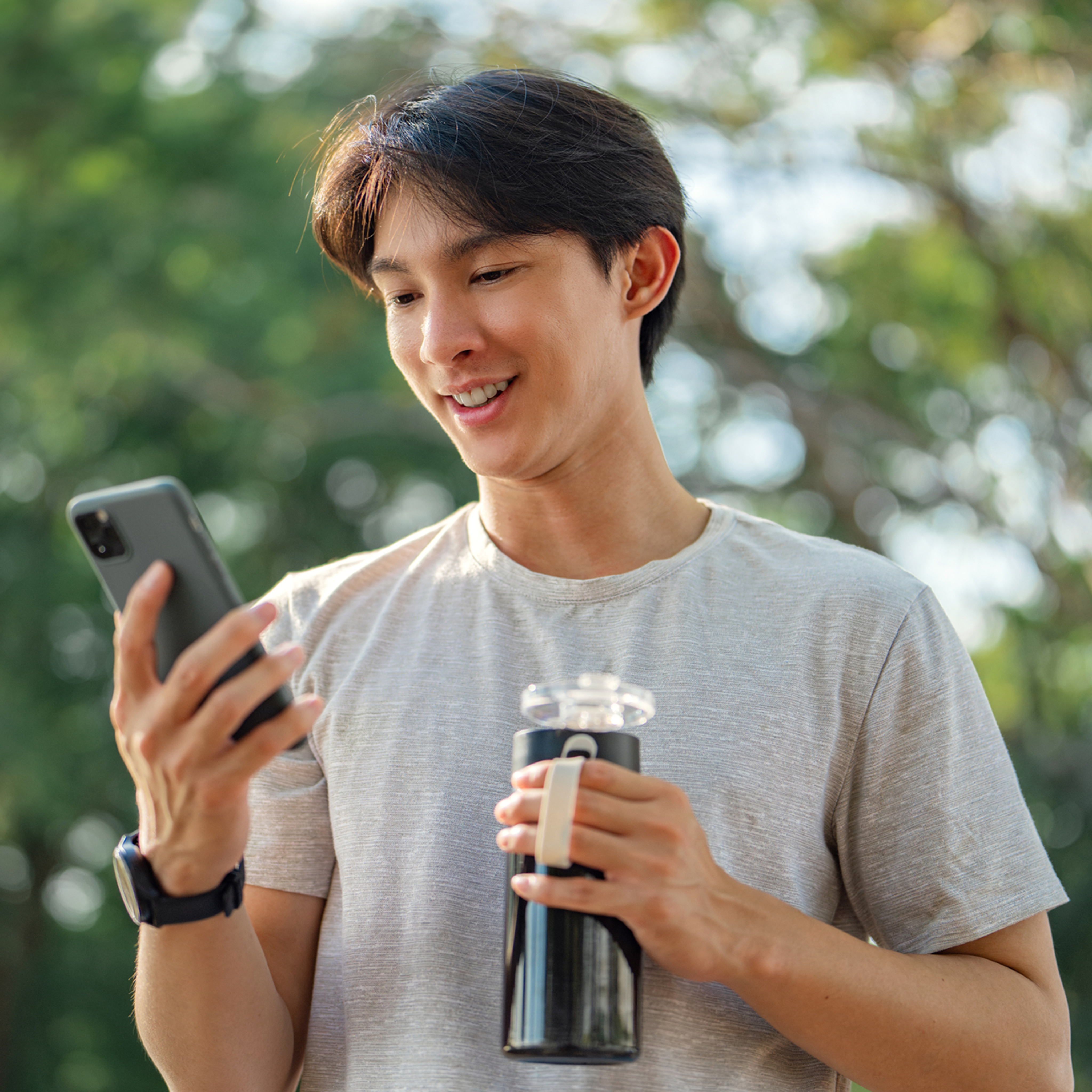 Young man on cell phone while holding a water bottle.