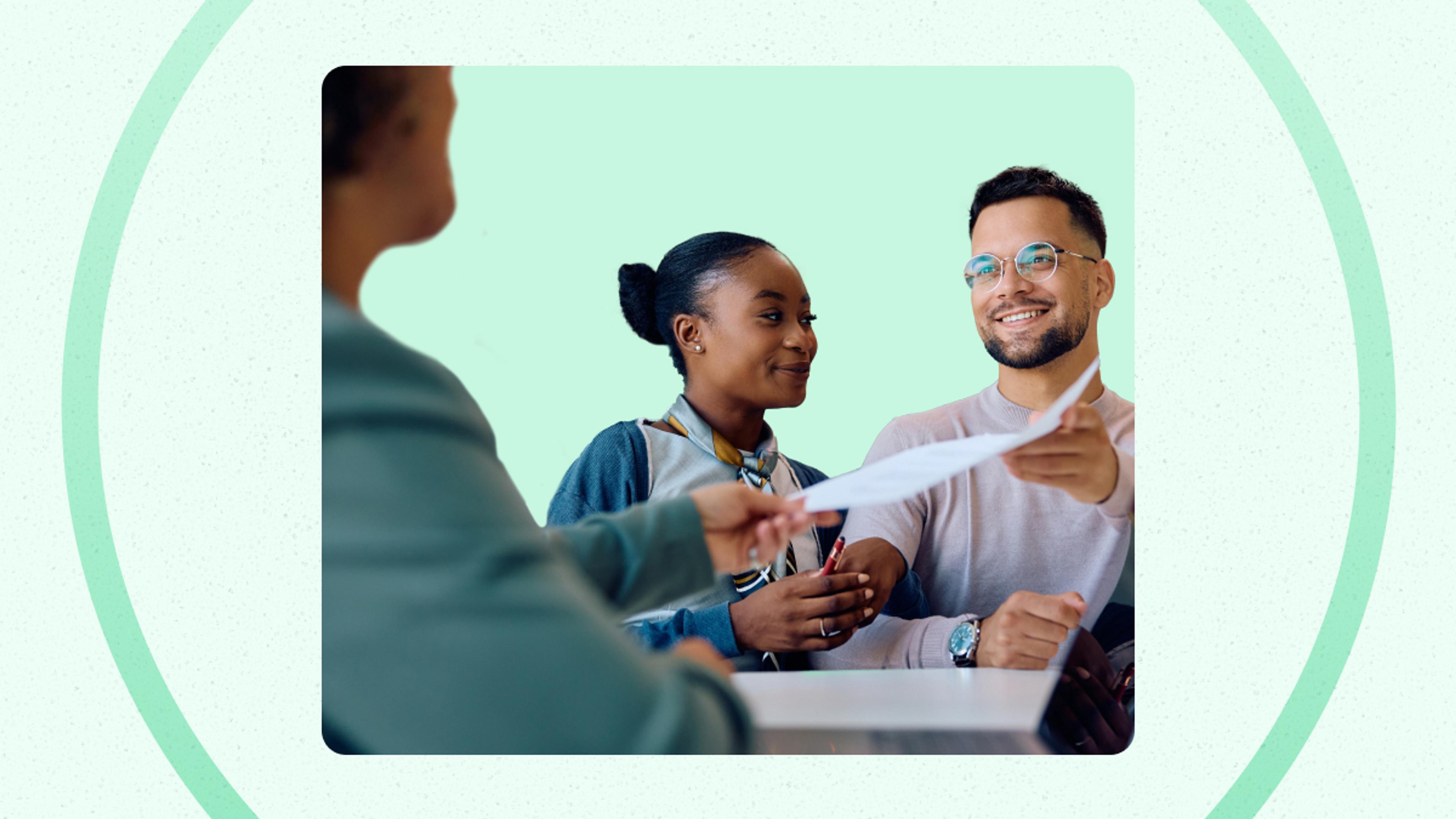 A person hands a document to a smiling man and woman sitting together at a table, against a green background.