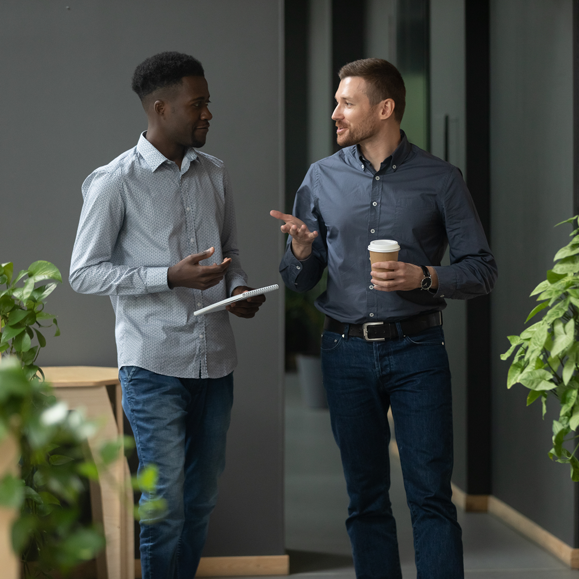 two men standing and talking in office one with coffee