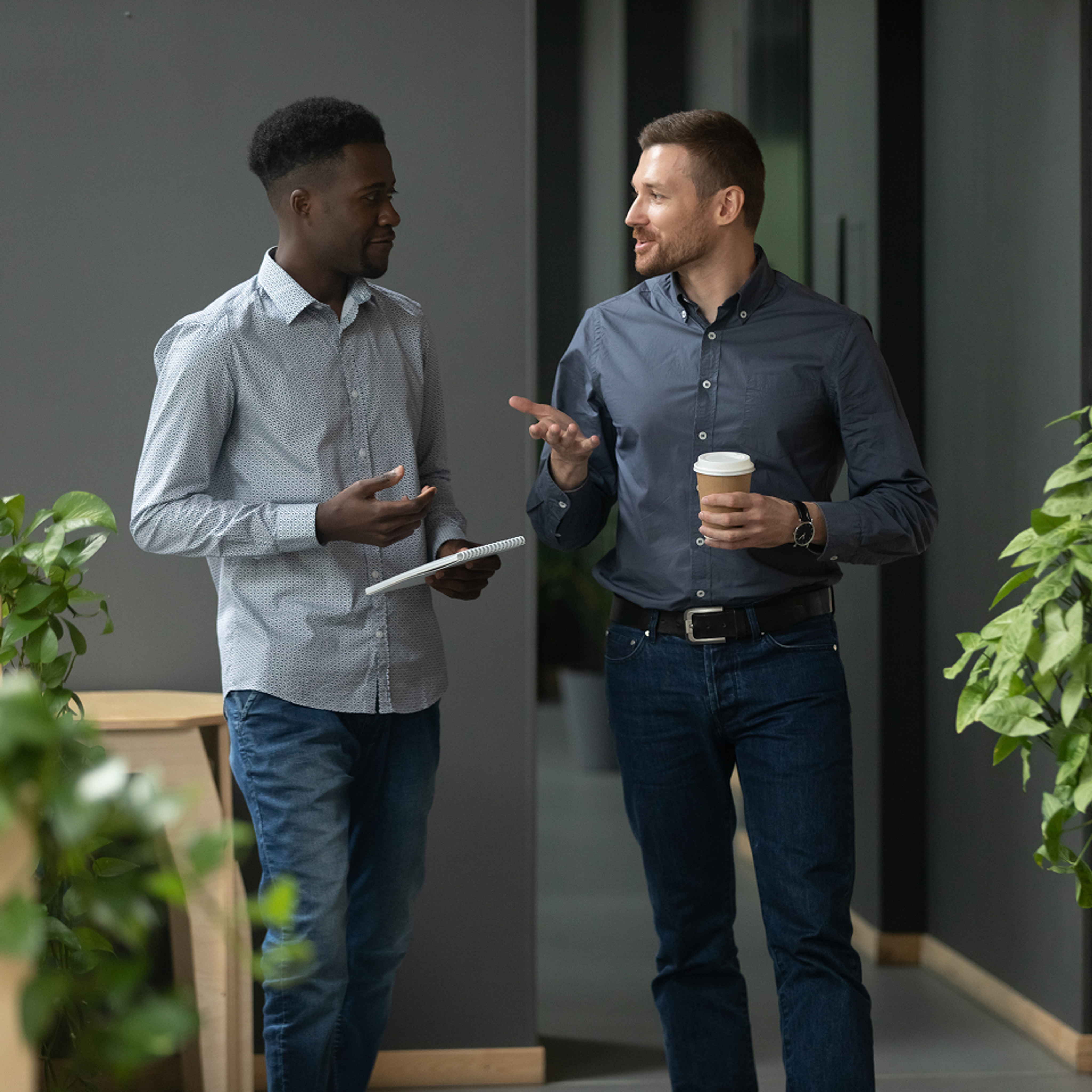 two men standing and talking in office one with coffee