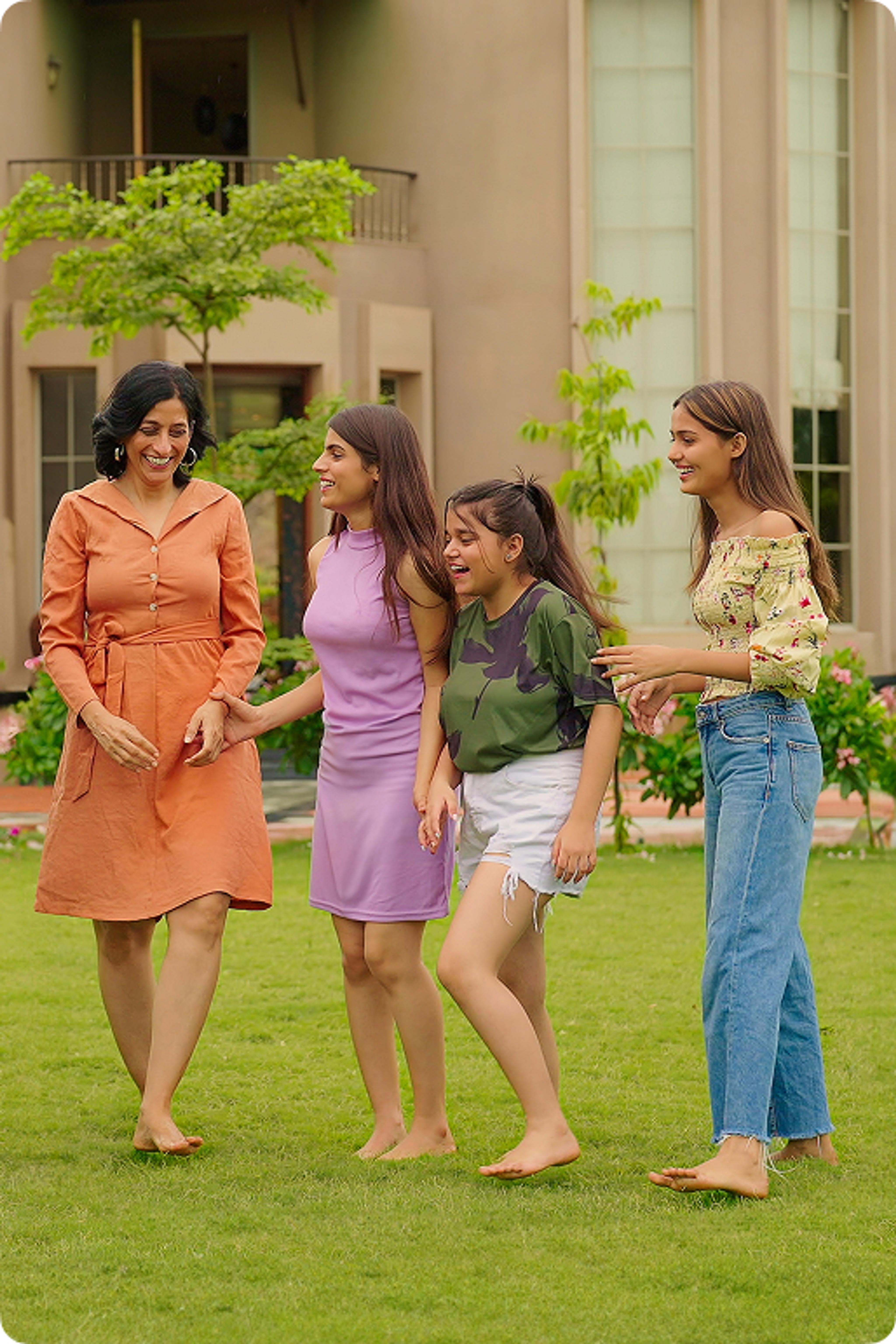 A woman and three young daughters smiling together outside.