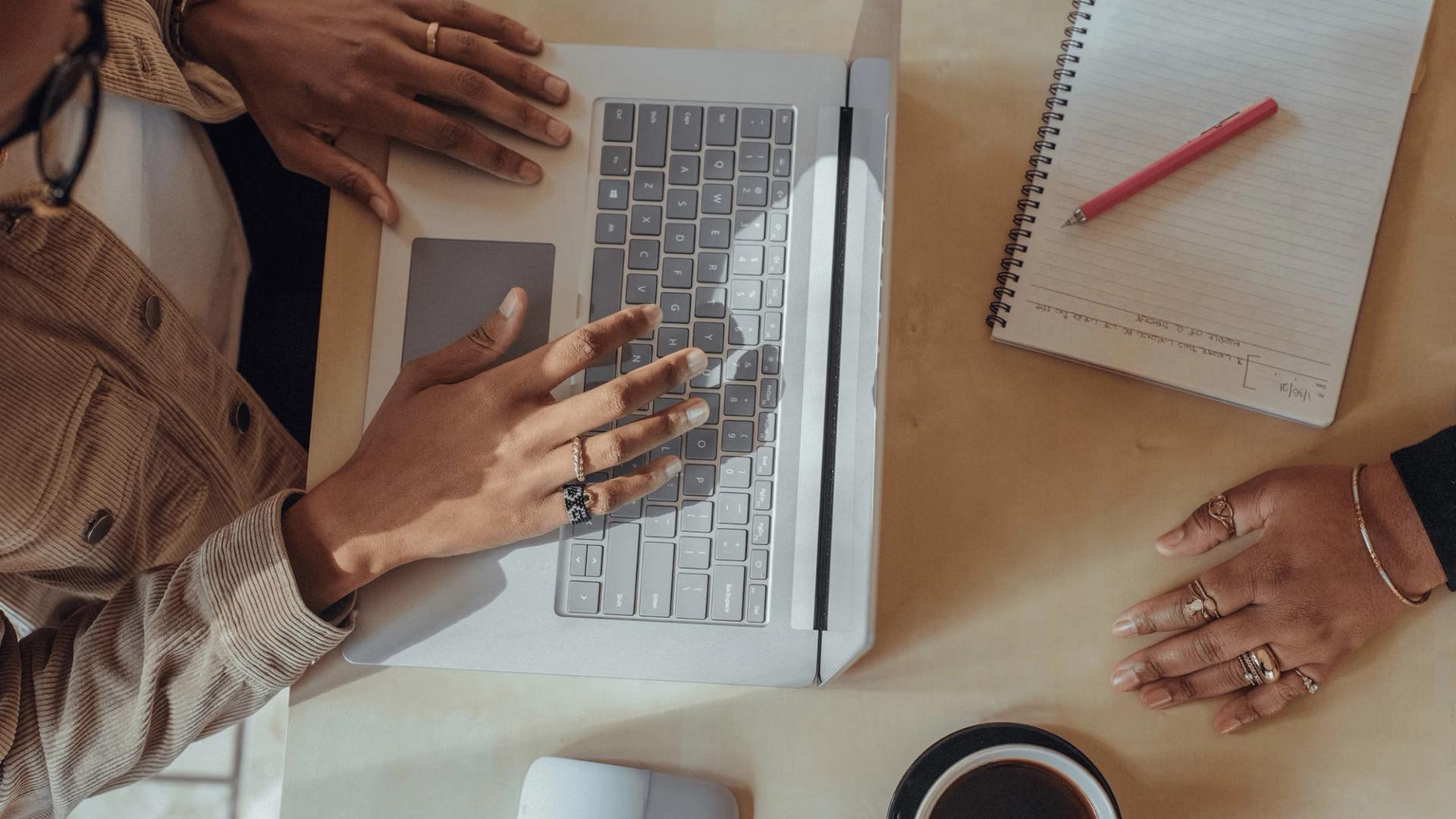 Hands hover over the keyboard of a laptop in an office setting