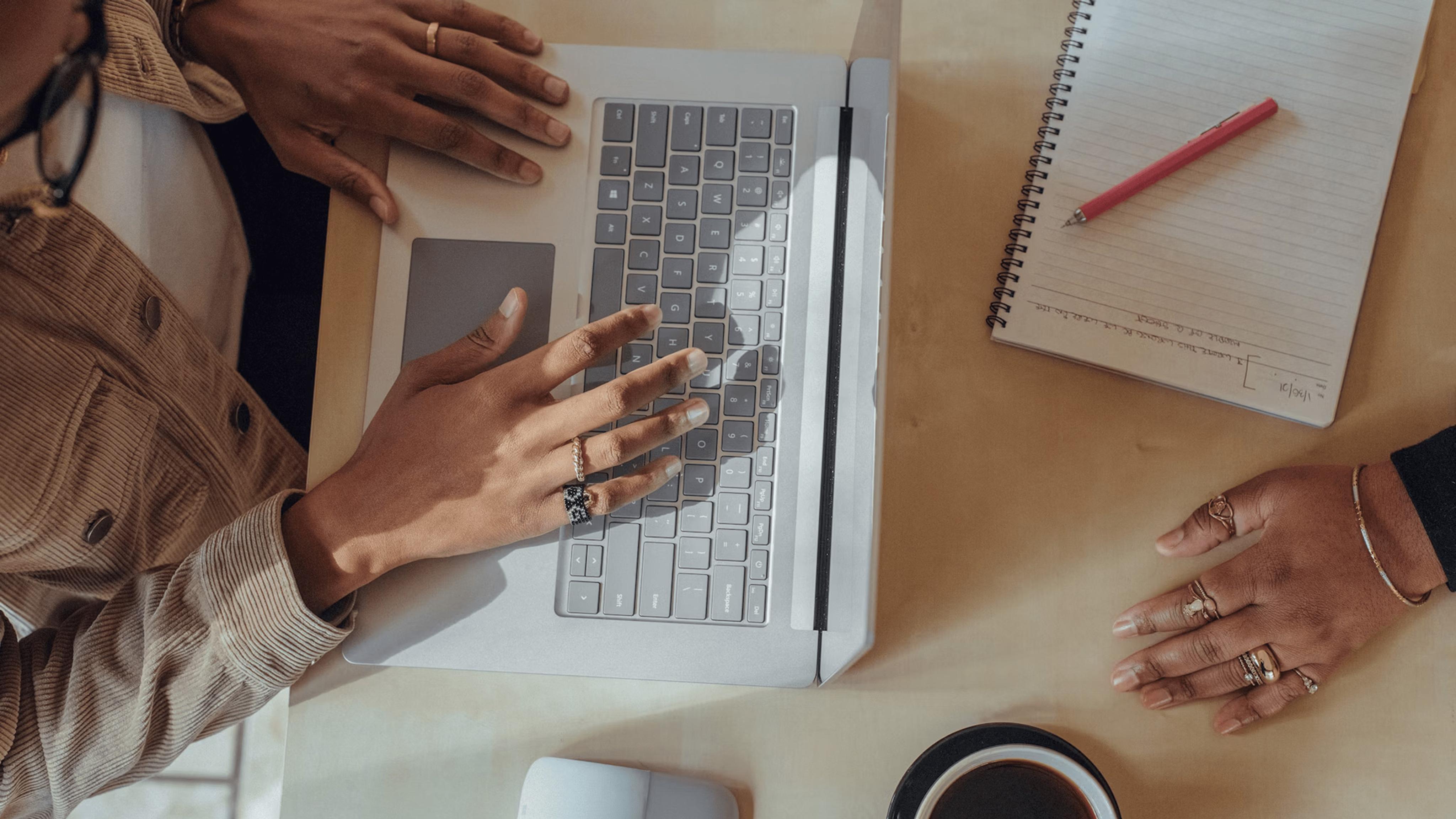 Hands hover over the keyboard of a laptop in an office setting