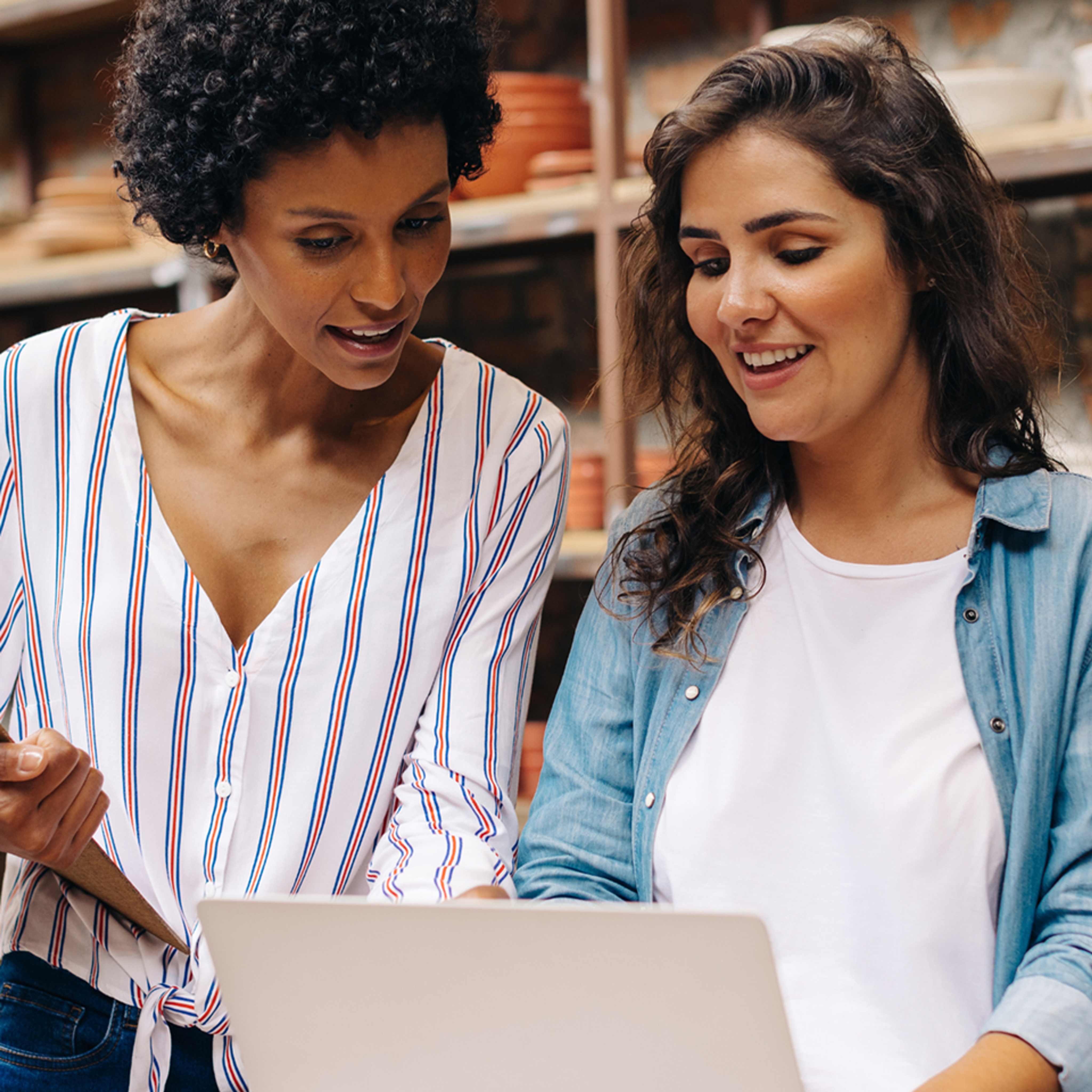 Two women working together as they look at a computer. 