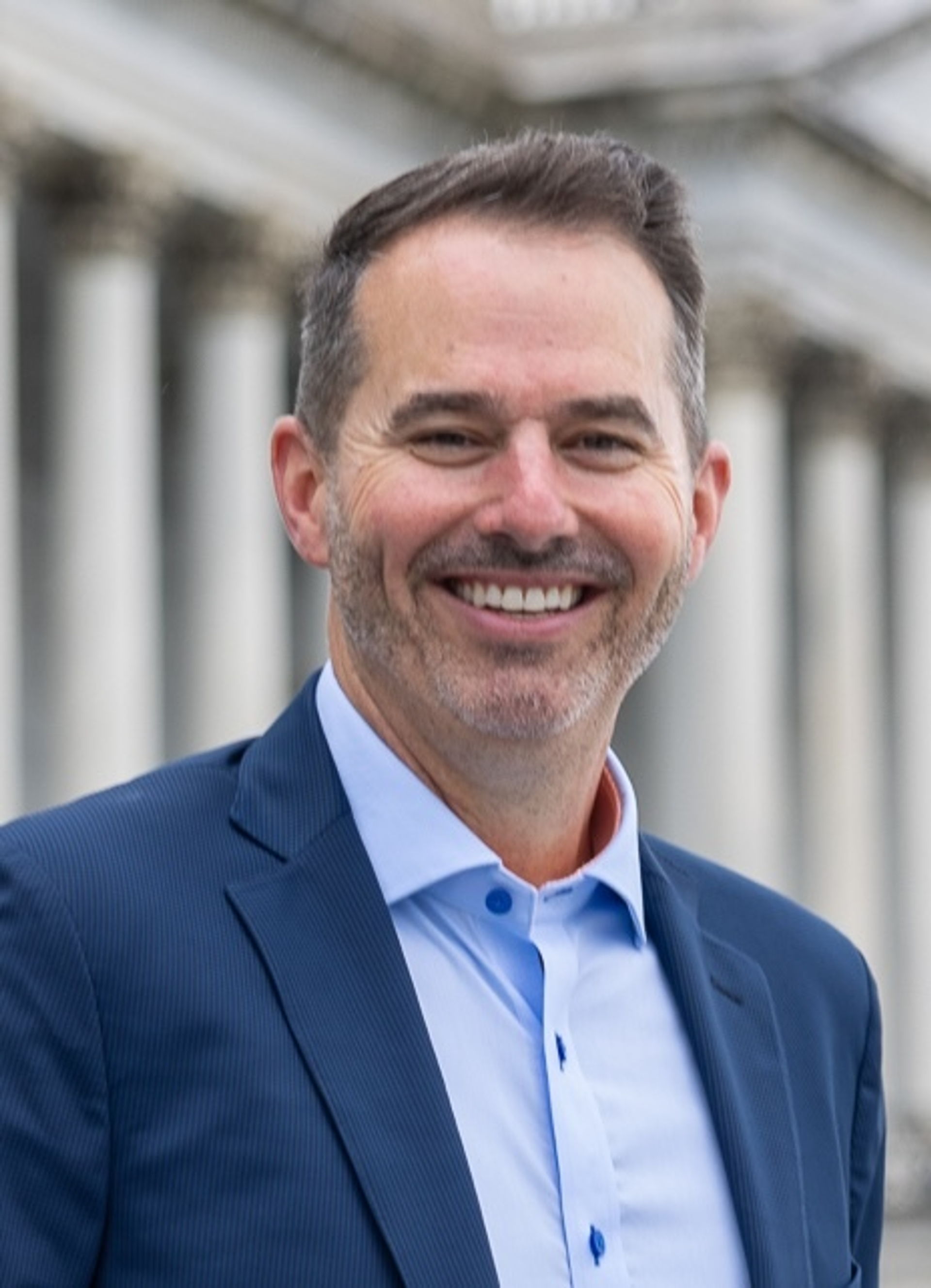 Photo of Senior Vice President David Bell smiling in front of a government building