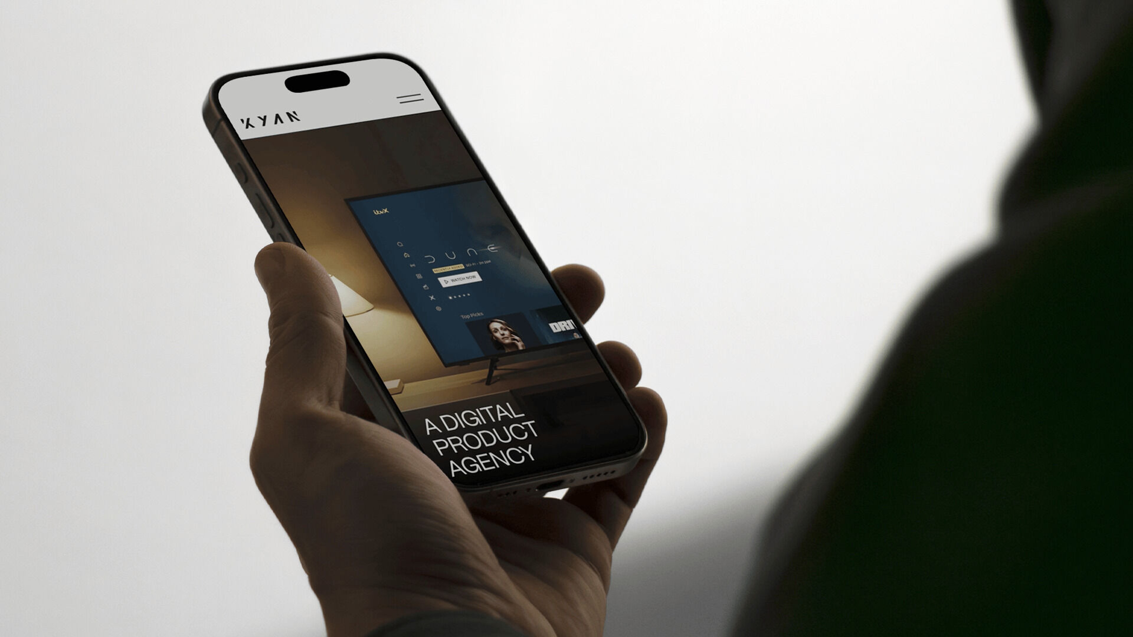 Hand holding a smartphone displaying a digital product agency website on the screen