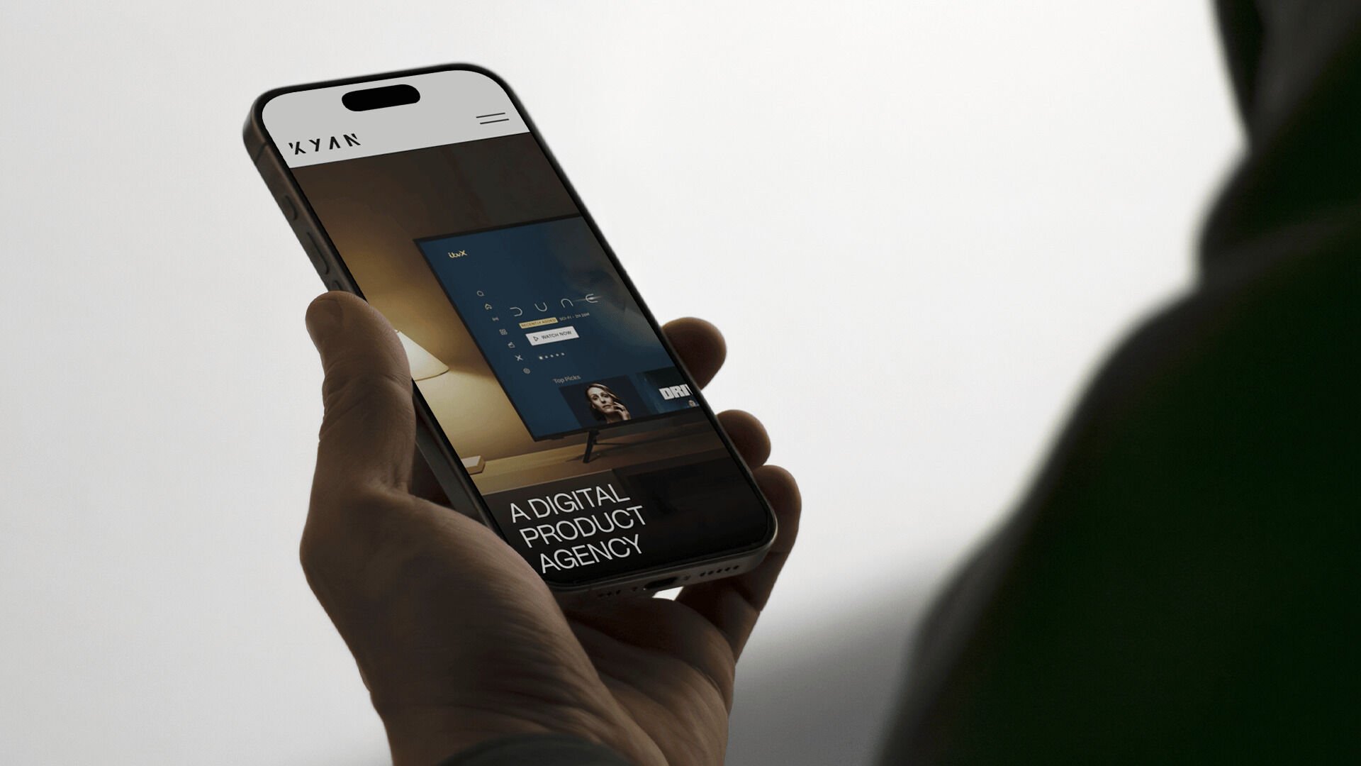 Hand holding a smartphone displaying a digital product agency website on the screen