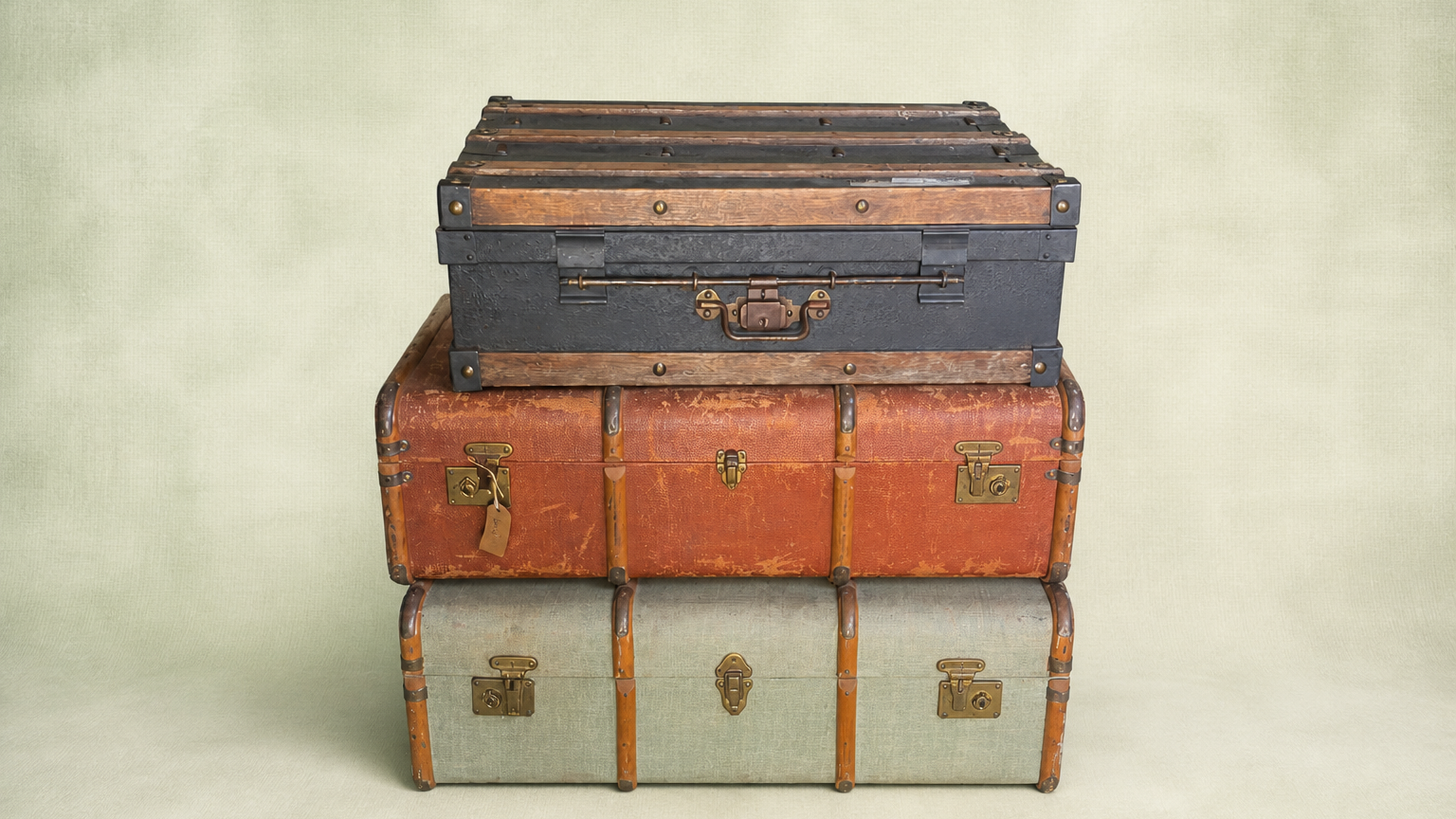 Set of three stacked vintage suitcases and trunks with brass latches