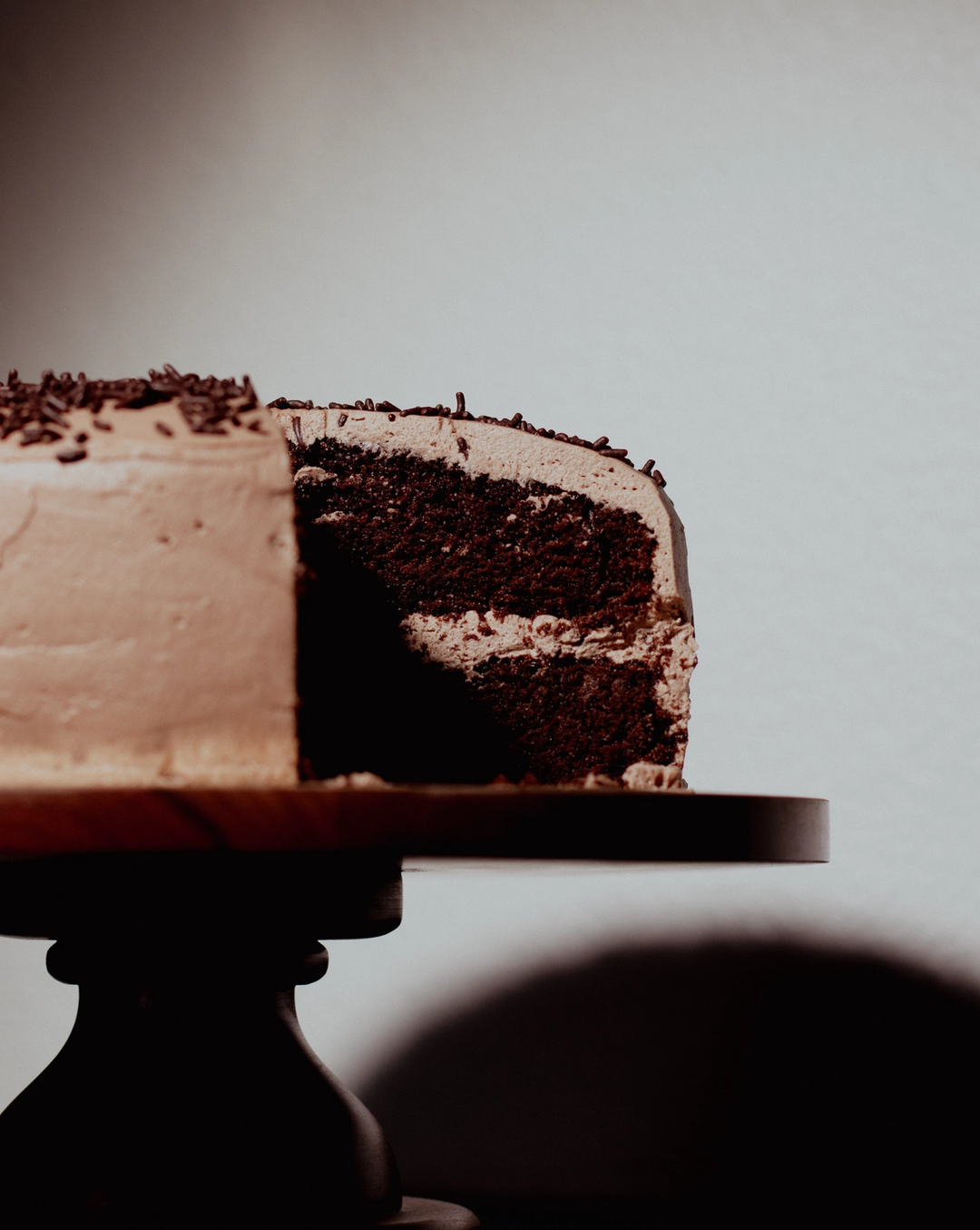 Chocolate layer cake with whipped icing on a wooden stand