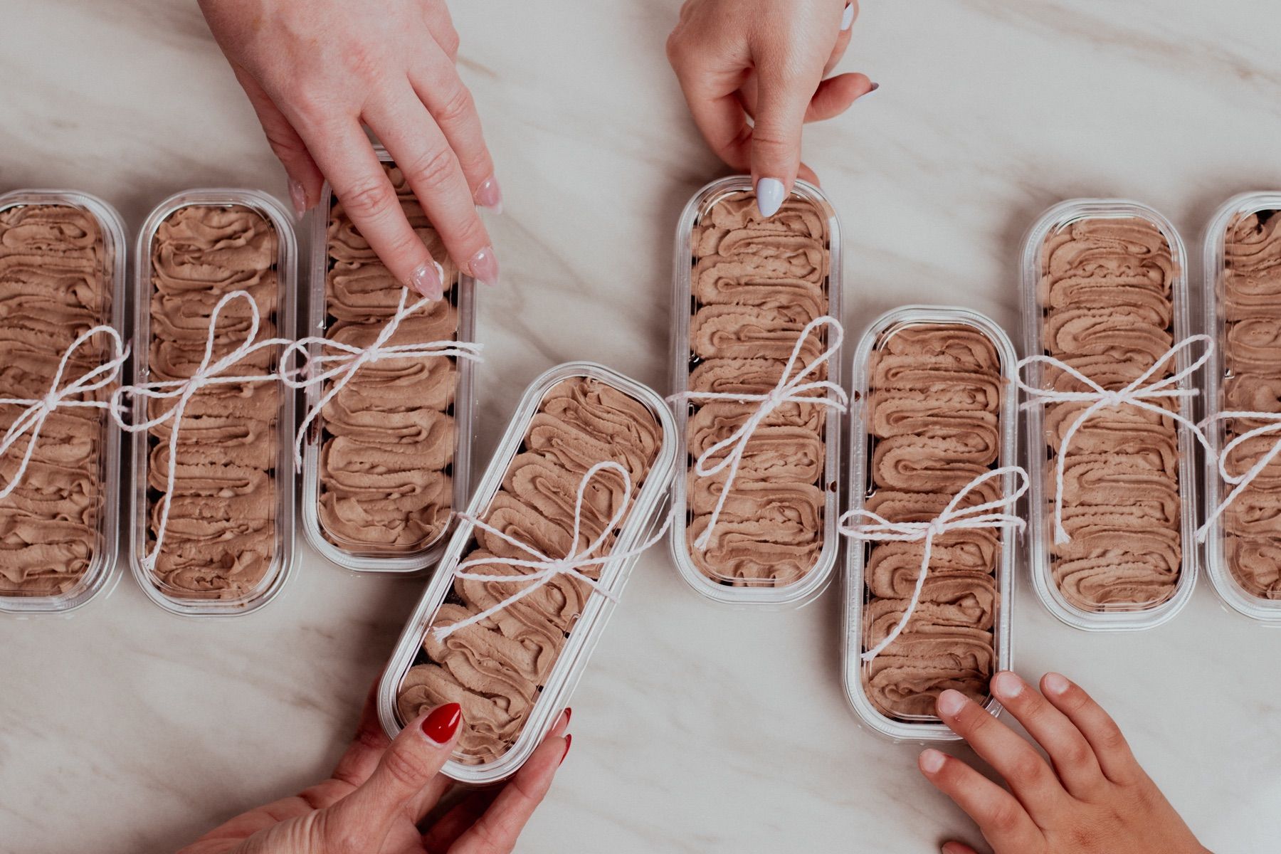 Several to-go containers of chocolate cake tied with white string