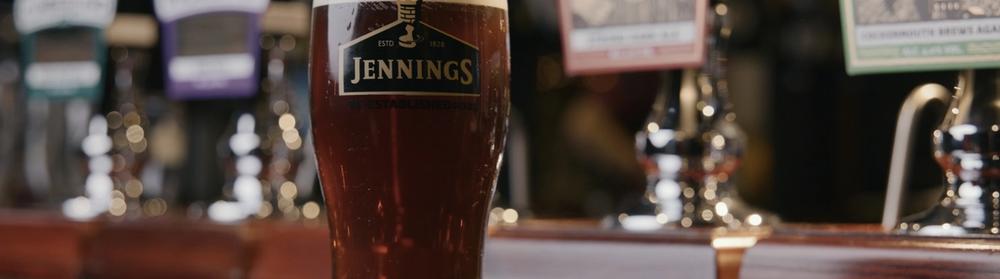 A pint of dark ale in a Jennings glass, the Sneck Lifter pump clip behind