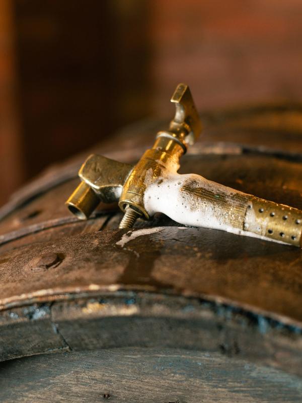 A brass tap set into a wooden cask, froth around its base