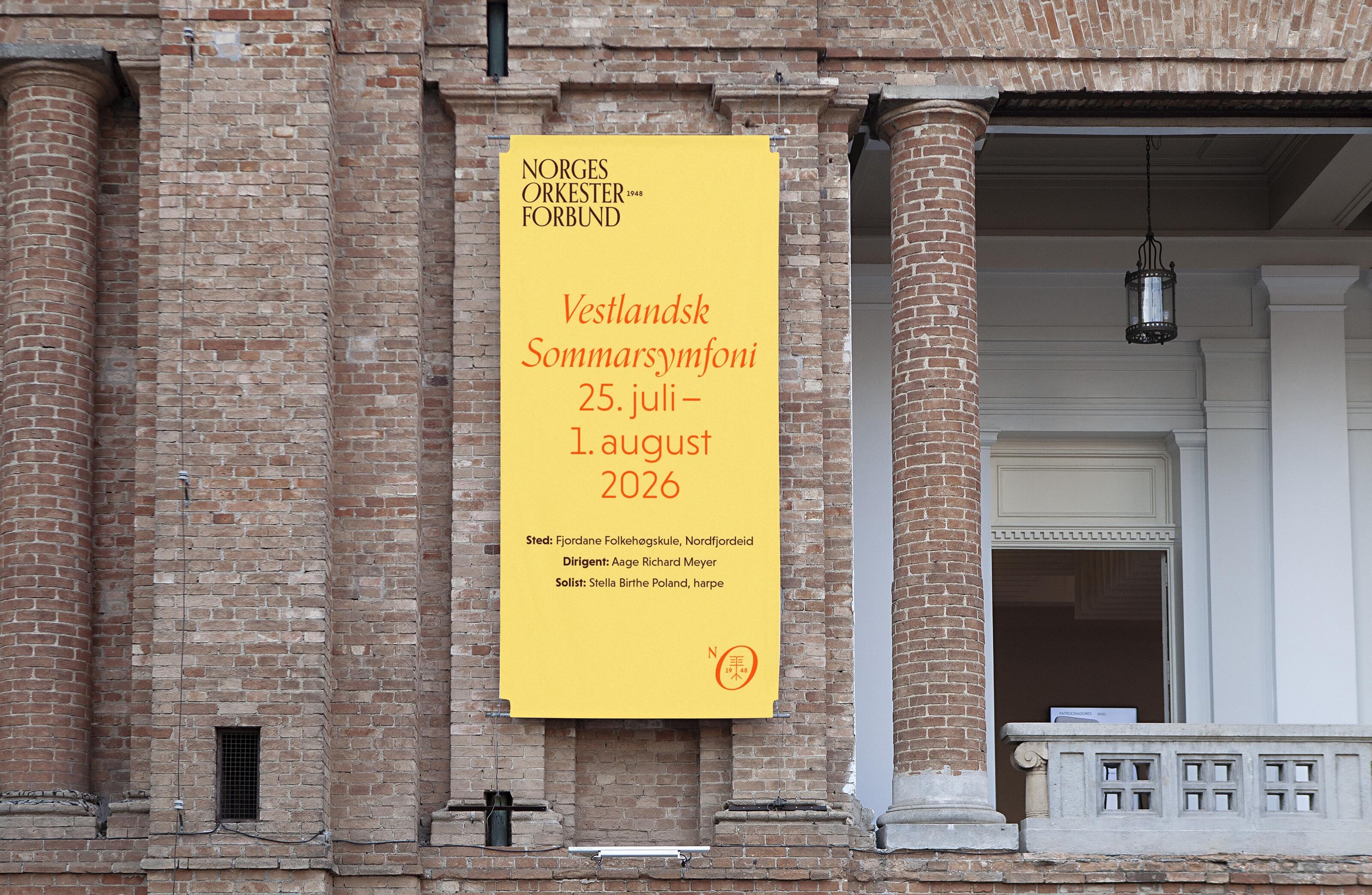 Big branded banner hanging in front of a brick building.