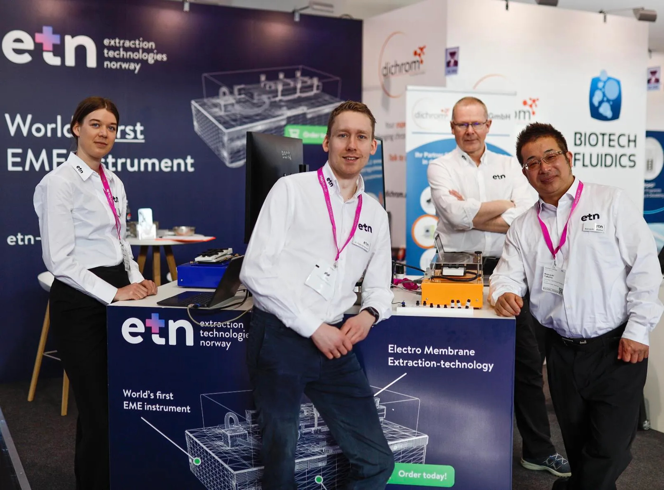 Four people in white shirts with 'etn' logos posing at a booth for Extraction Technologies Norway showcasing their Electro Membrane Extraction technology.