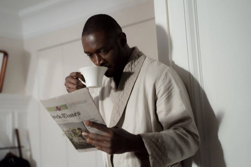Man in ochtendjas leest de krant met een kop koffie, ontspannen ochtendmoment