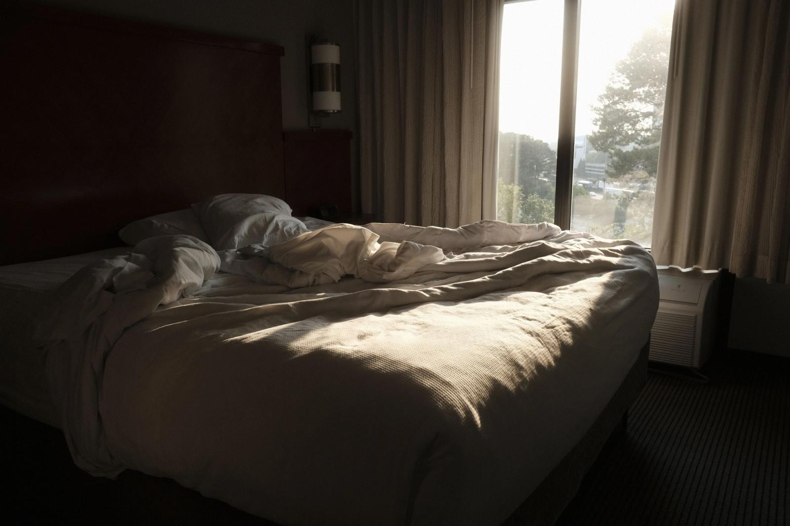 Onopgemaakt bed met zacht ochtendlicht door het raam