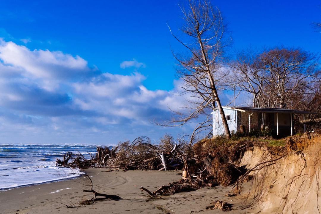 A house looms dangerously close to the eroded coast. Previously, this house would have been thousands of feet from the beach.