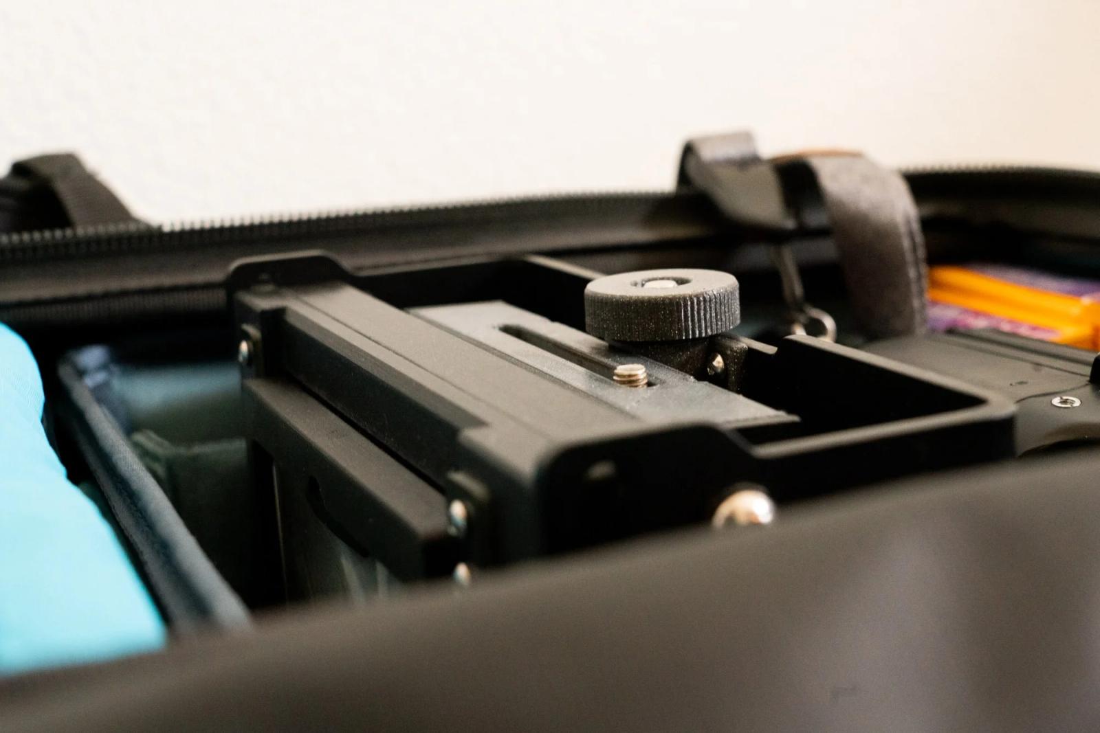 The 4x5 camera in a Shimoda Medium DSLR insert. Note three things. 1: how the camera protrudes above the insert (left side) and almost sits flush with the zipper. 2: The zipper and backpack material are being supported only by the frame of the camera insert. 3. There is no extra material visible from the zipper or bag.
