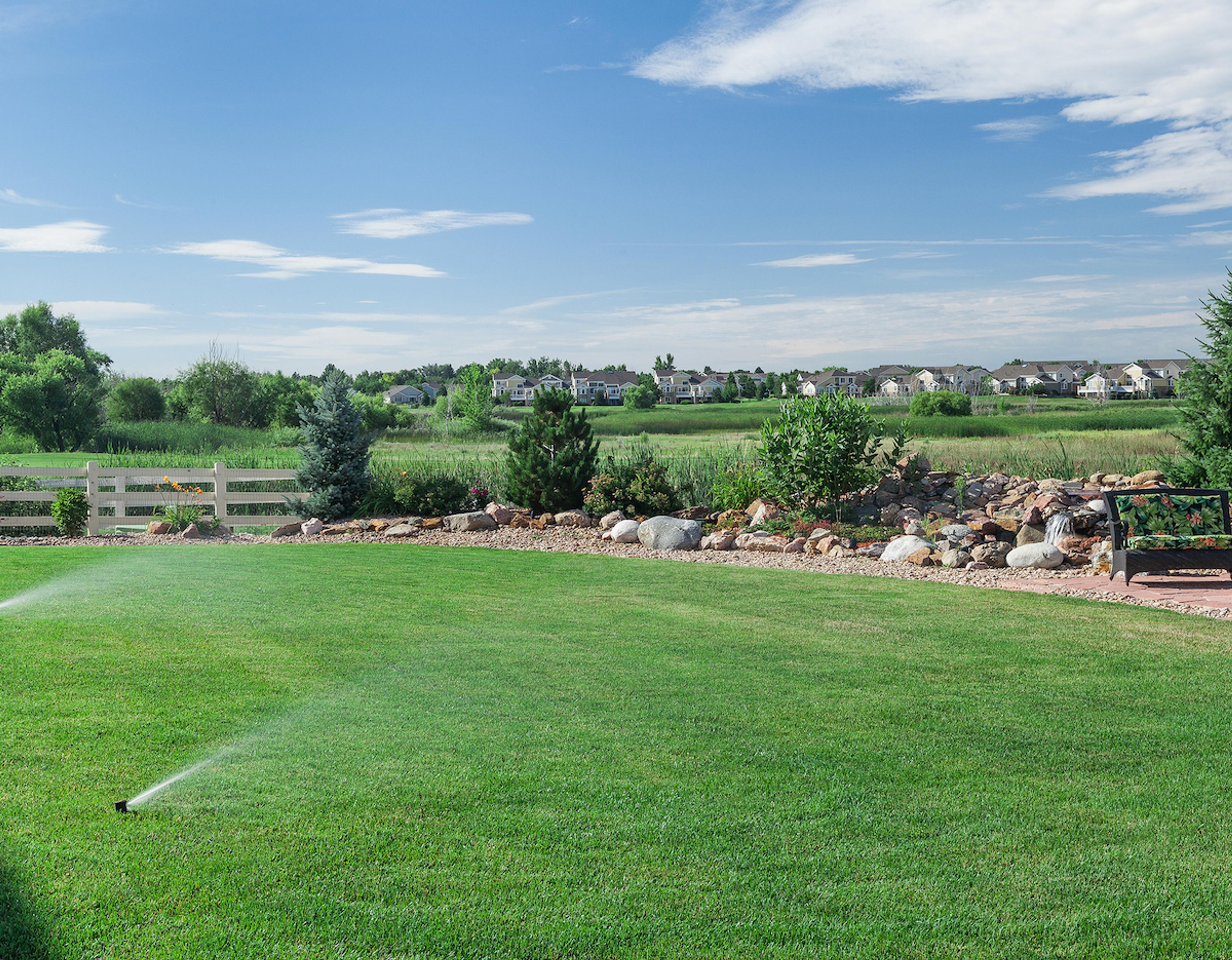 Sunny day with bright green lawn and working sprinklers