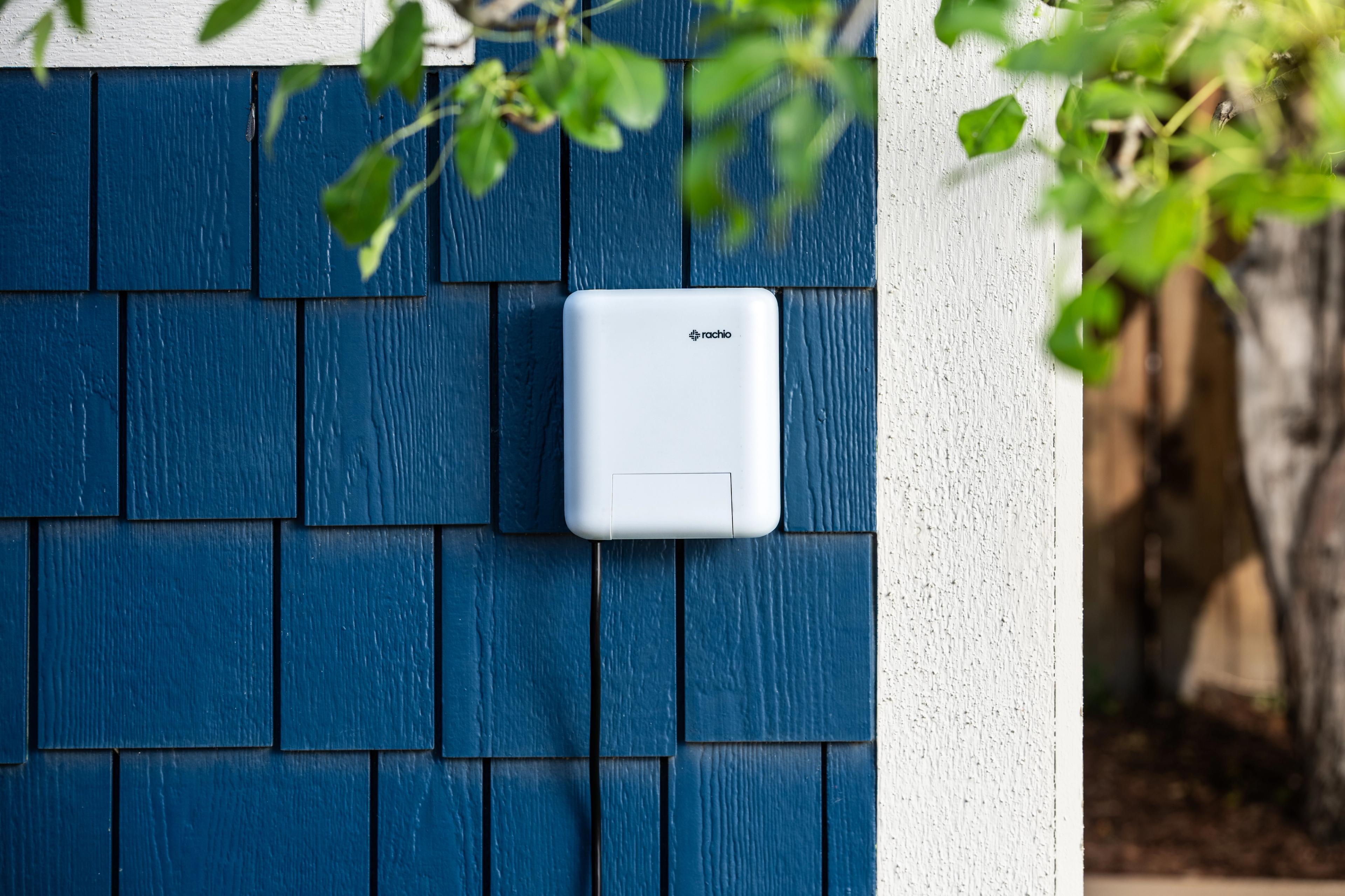 Rachio smart lighting controller mounted on blue exterior home