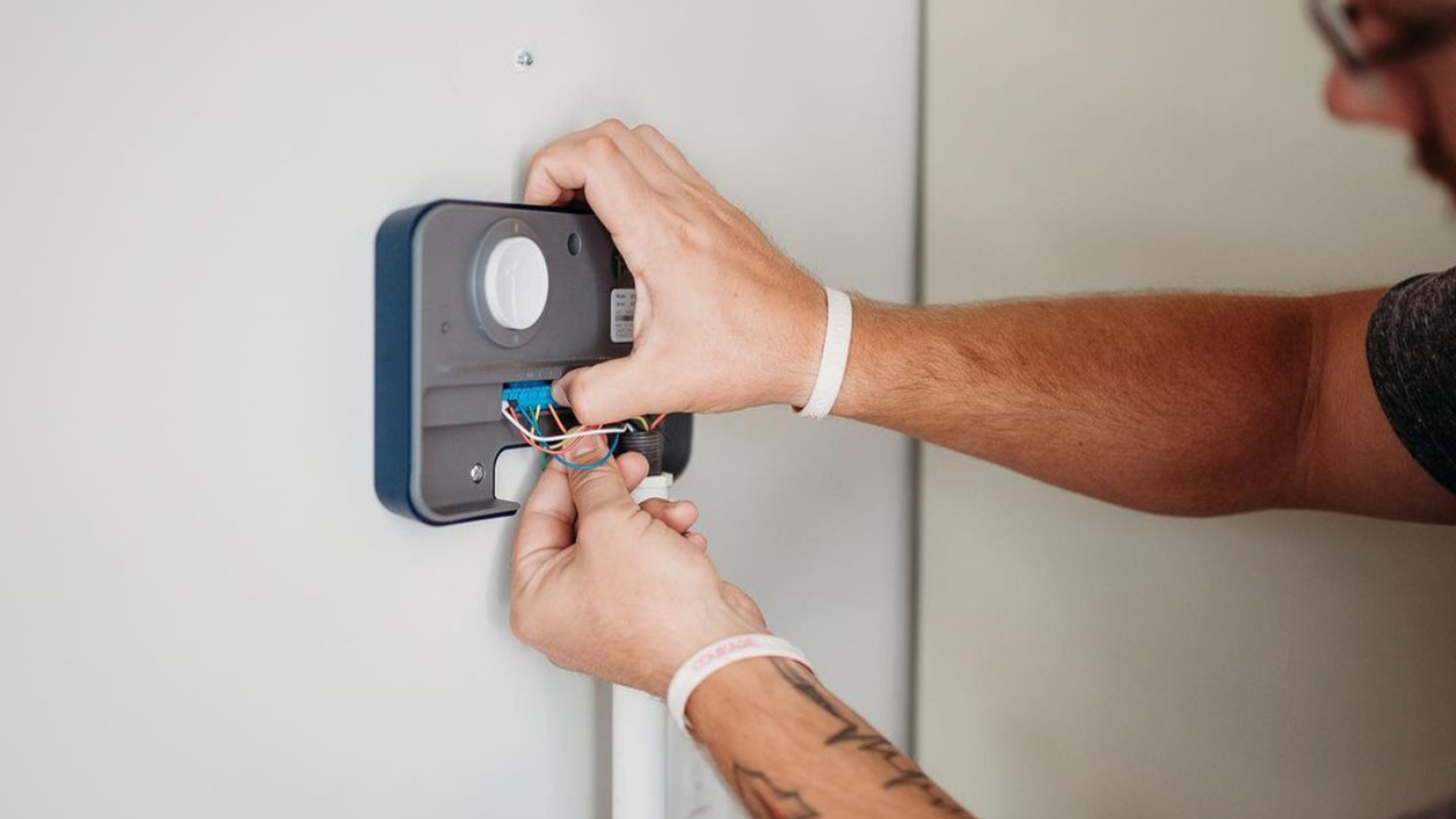 Rachio Smart Sprinkler Controller installed on a wall paired with app screen