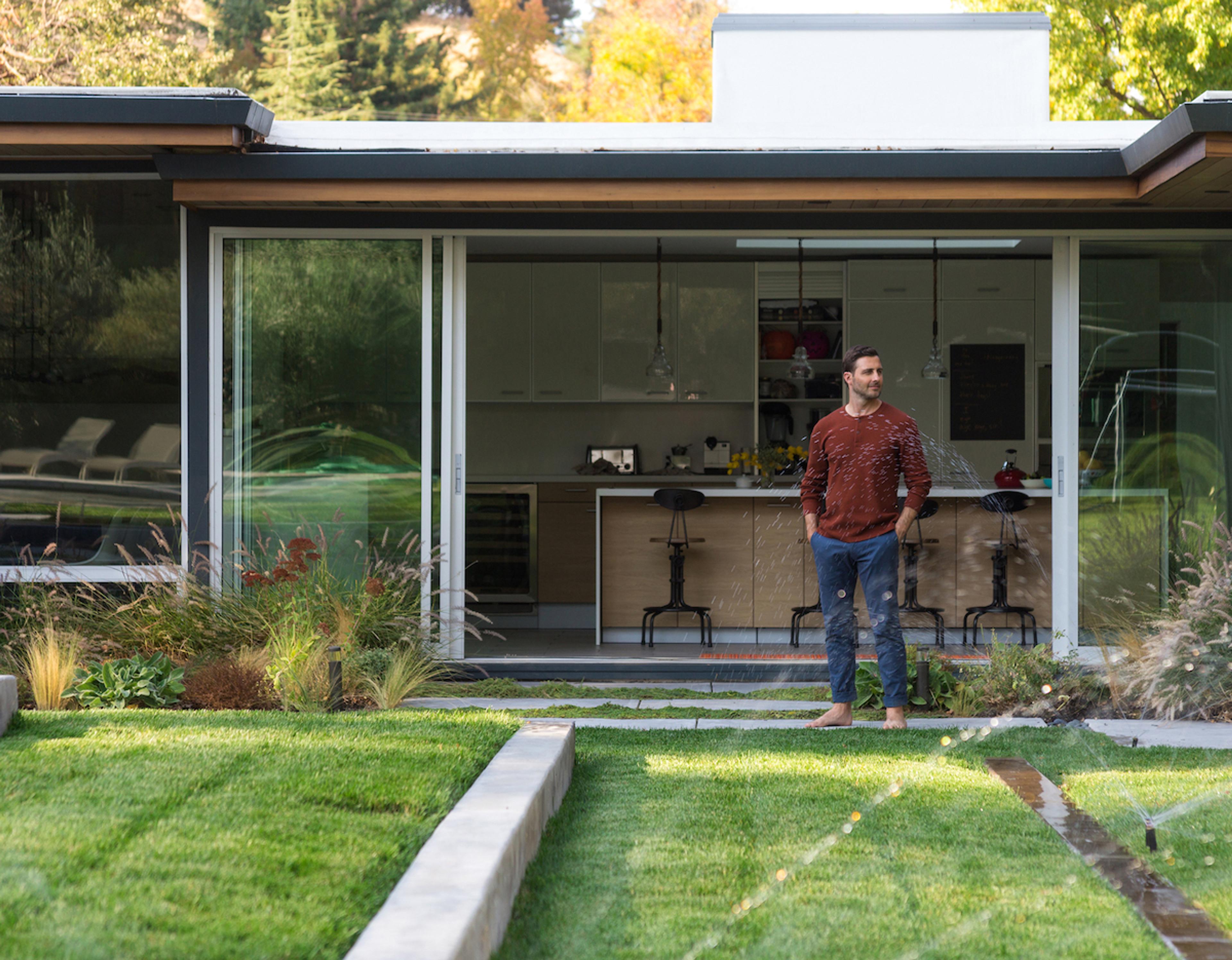 Man admiring his lawn with working sprinklers