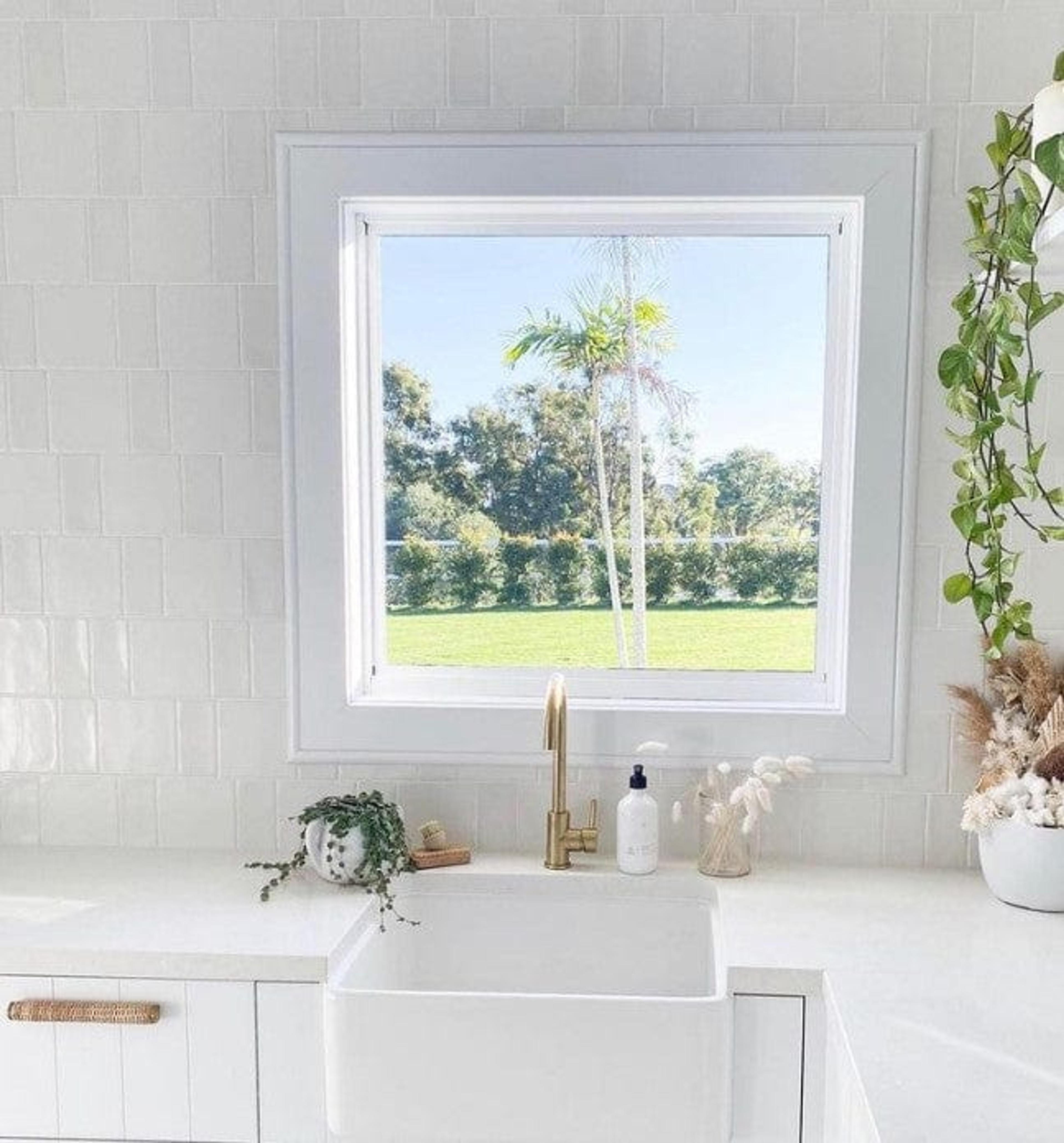 Kitchen with golden taps and modern square sink with view towards the garden