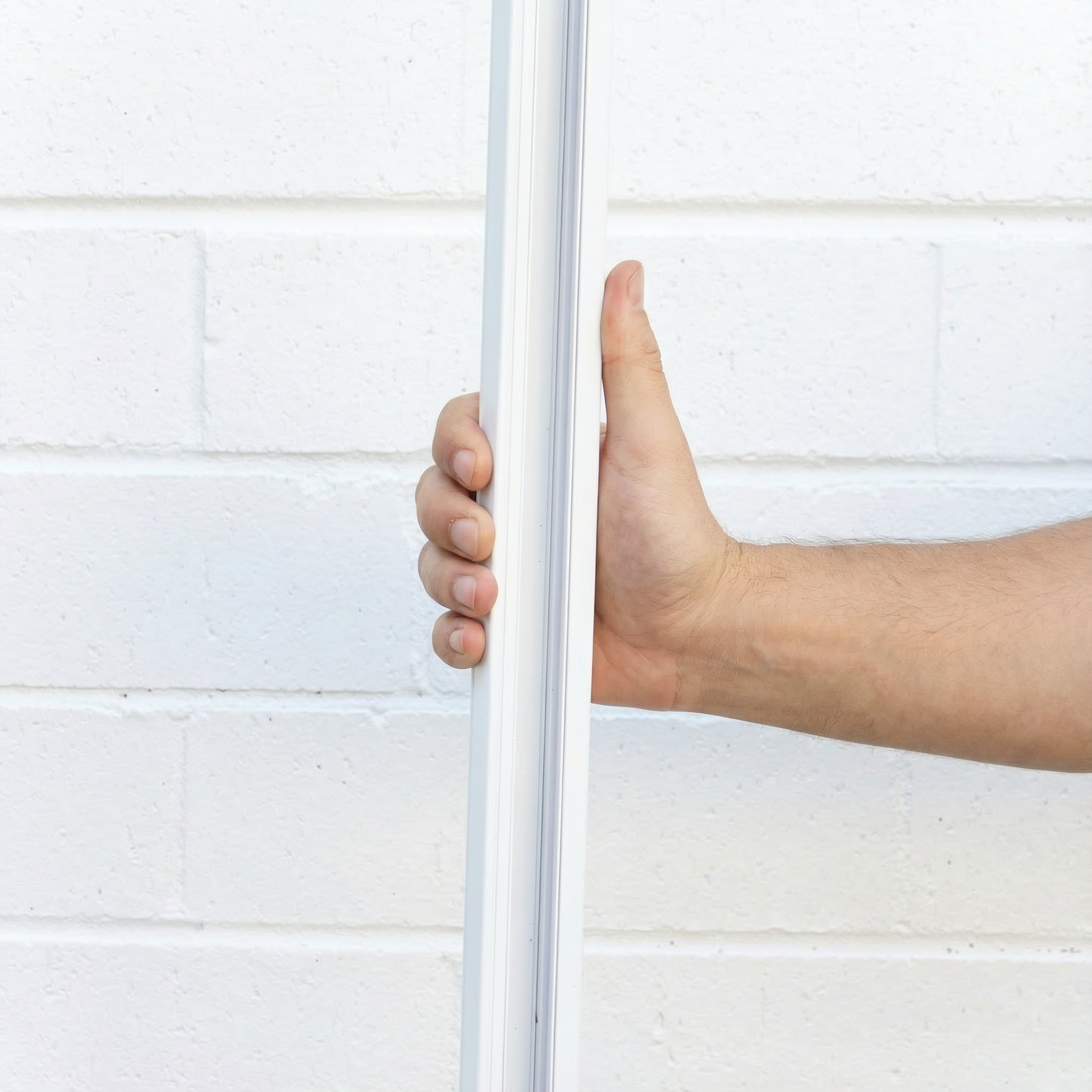 Darlinghurst White Track held upright by hand against a white brick wall
