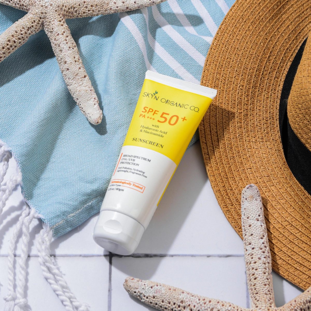 Tube de protection solaire SPF 50+ avec un chapeau de paille sur une serviette.