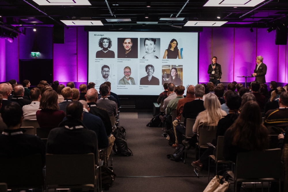 Medlemmer av KI-utvalget på skjermen. Administrerende direktør Steinar Skjerdingstad og Christian Hofmeier, fagansvarlig digitale verktøy, på scenen. (Foto: Caroline Glasius-Nyborg)