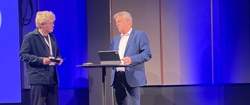 Administrerende direktør, Steinar Skjerdingstad, i Arkitektbedriftene og statsråd Bjørnar Skjæran i samtale på scenen under "By og land" i 2025. 28. april redegjør Skjæran for regjeringens videre arbeid for å nå målet i Plan for Norge om igangsetting av 130.000 nye boliger innen 2030.