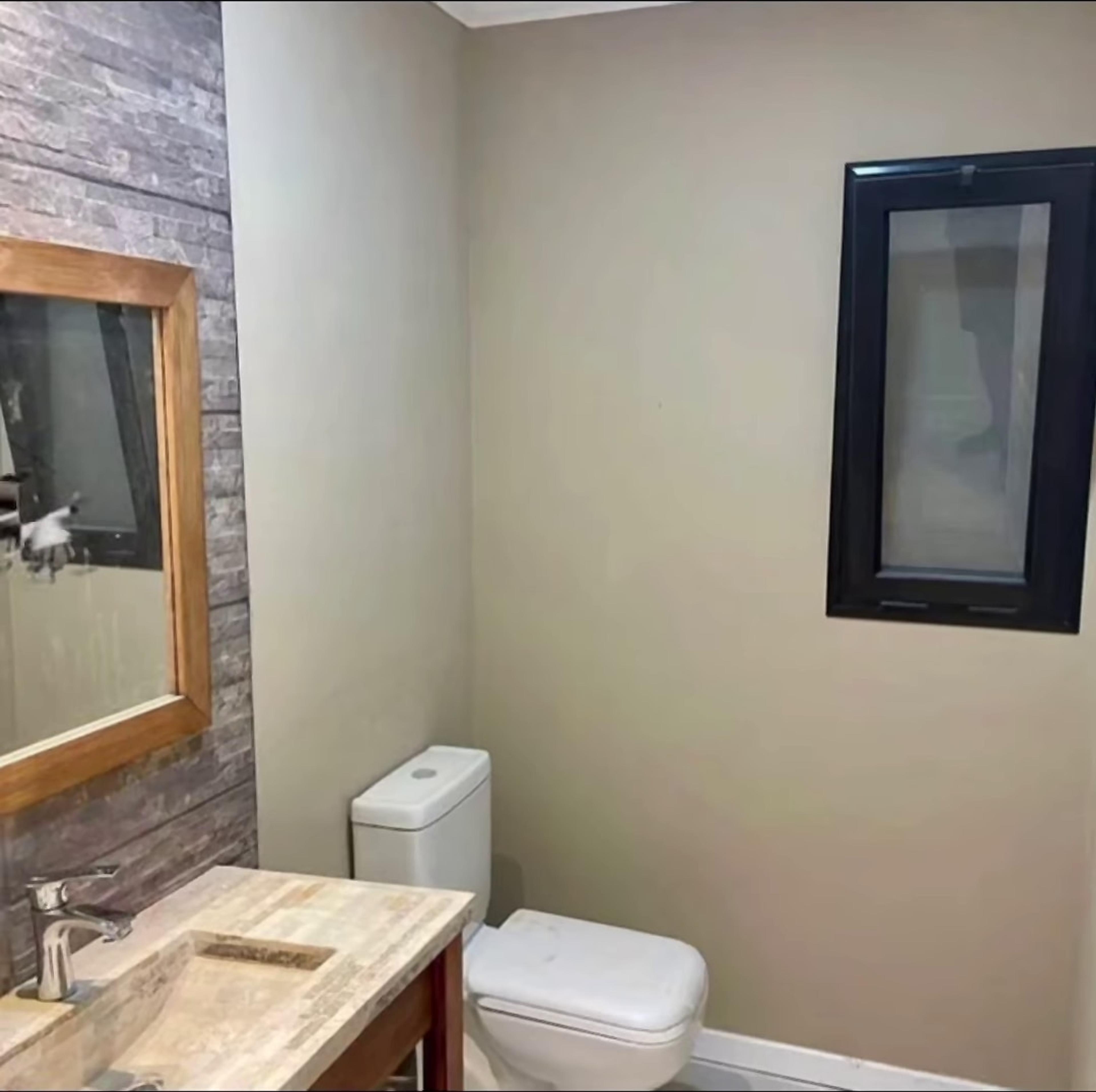 Baño con vanitory de madera y revestimiento de piedra