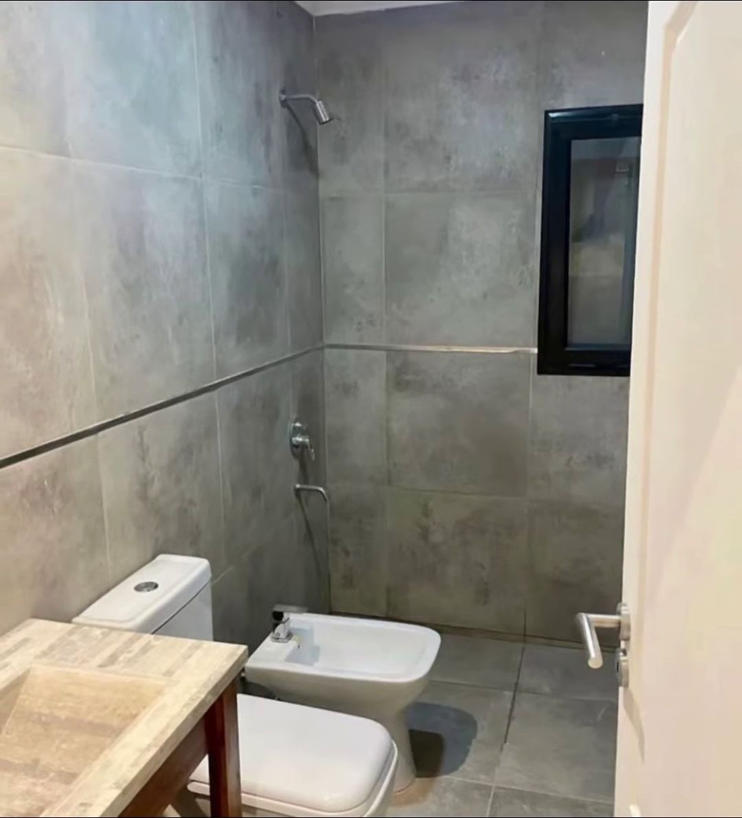 Baño con revestimiento de porcelanato gris y ducha