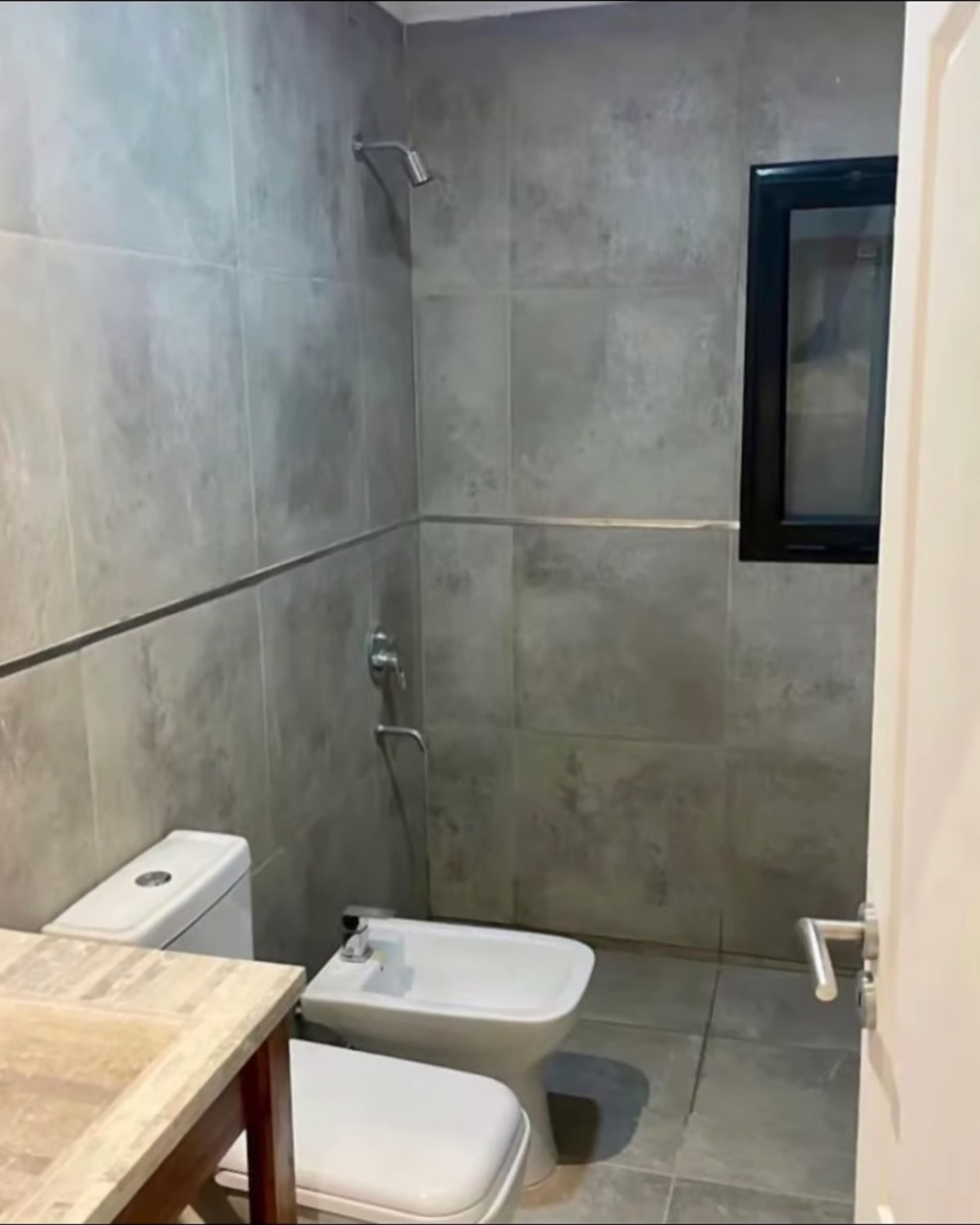 Baño con revestimiento de porcelanato gris y ducha