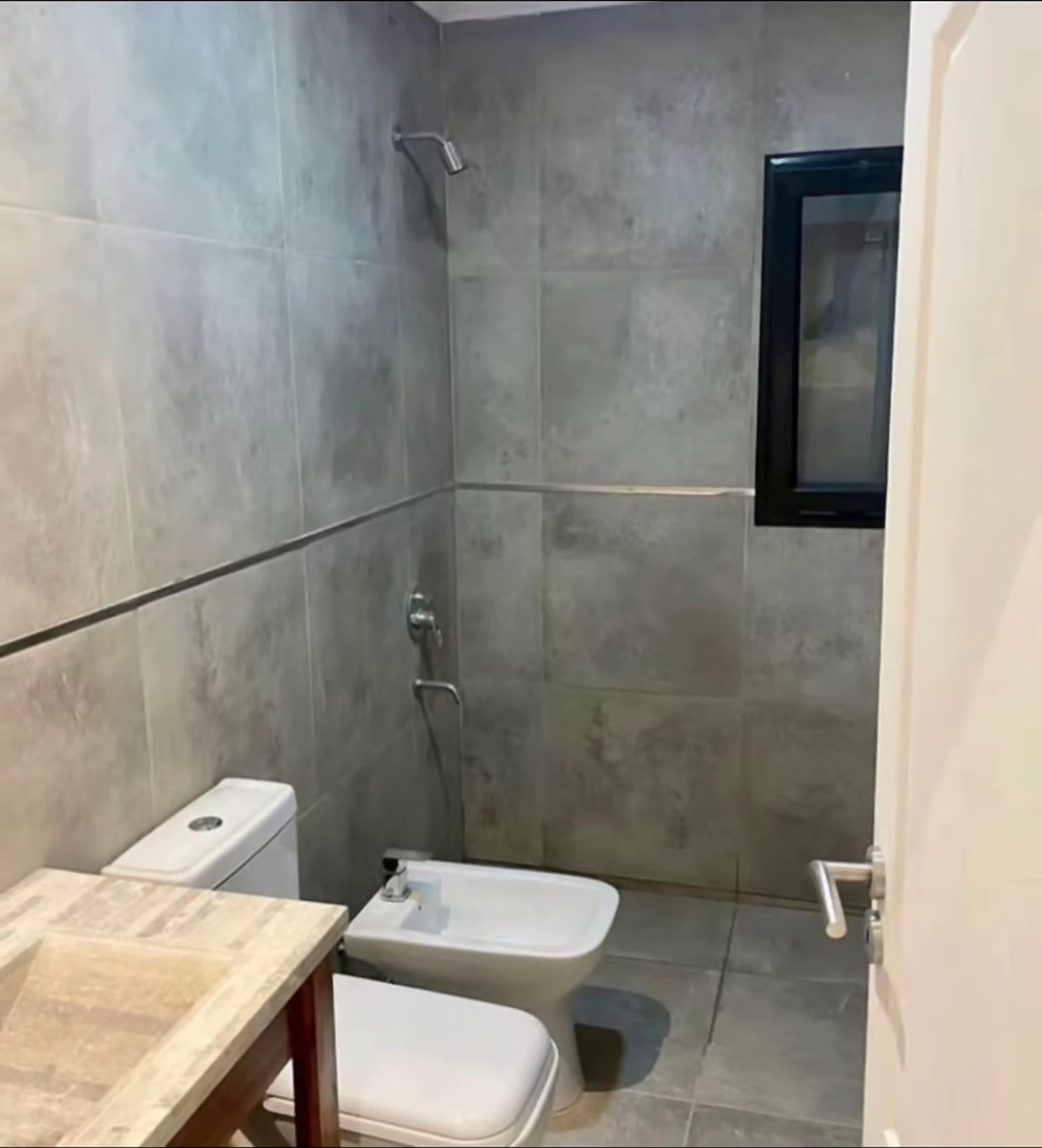 Baño con revestimiento de porcelanato gris y ducha
