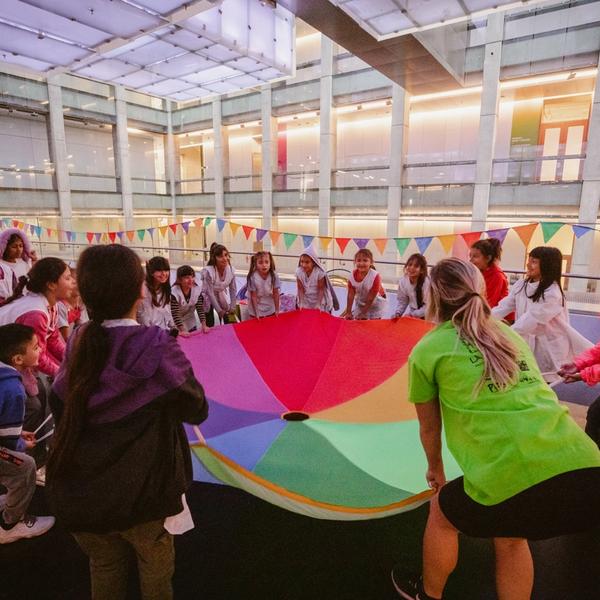 Alumnos de primaria sosteniendo una tela de multiples colores.