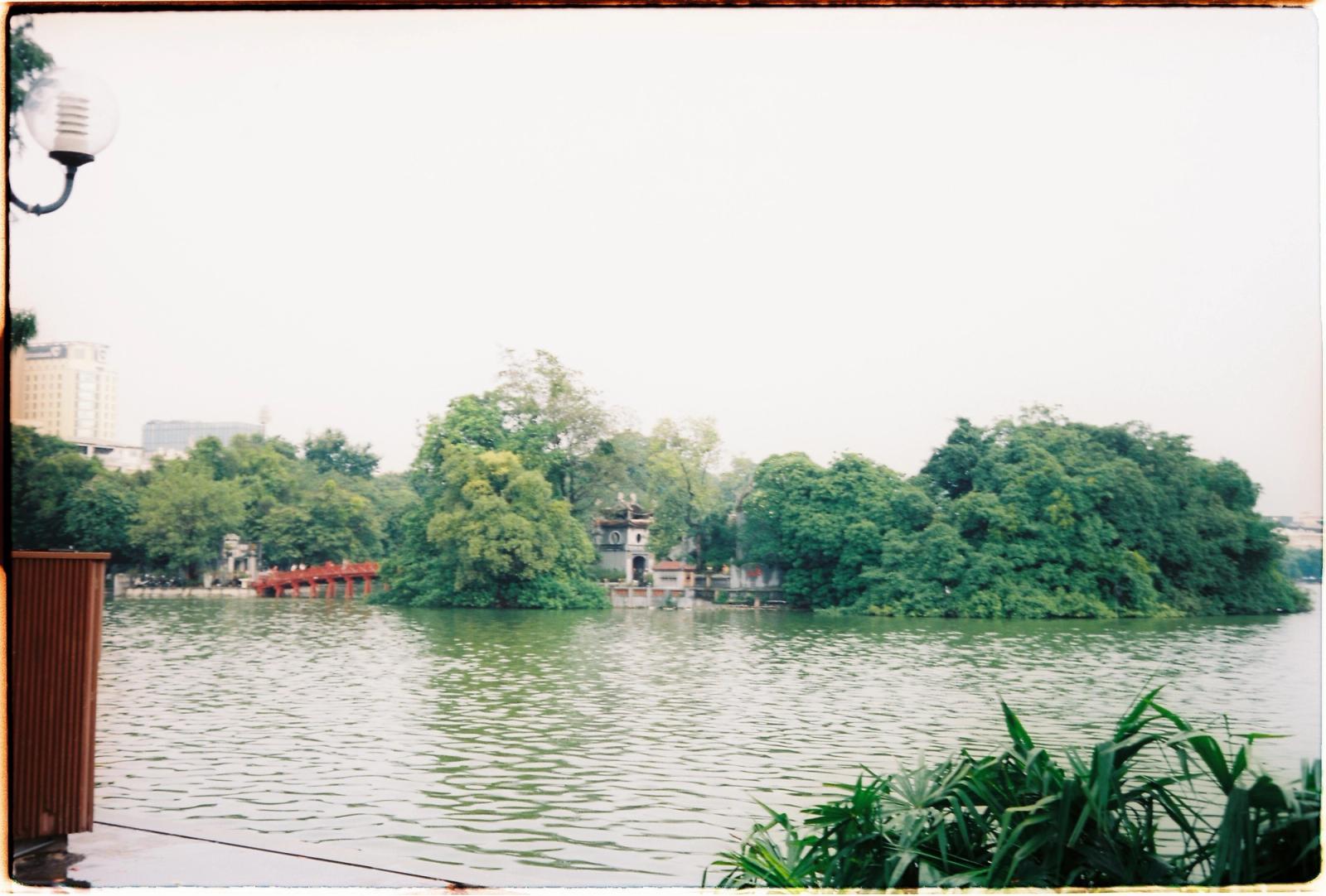 Serene view of Hoan Kiem Lake in Hanoi, featuring Ngoc Son Temple and lush greenery