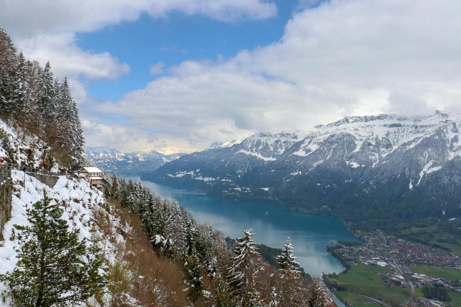 Mountainside viewpoint overlooking a turquoise lake and snow-dusted slopes