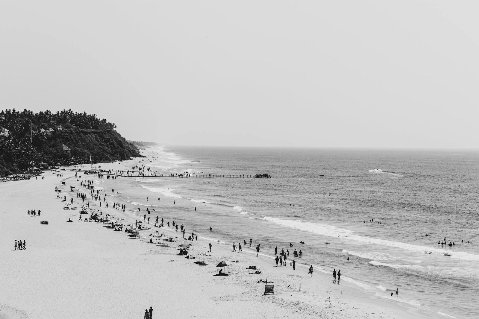Black and white view of a crowded beach meeting the ocean