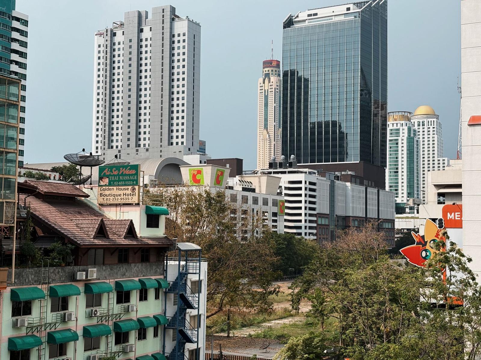 Street view of low-rise buildings and a boutique hotel sign among skyscrapers