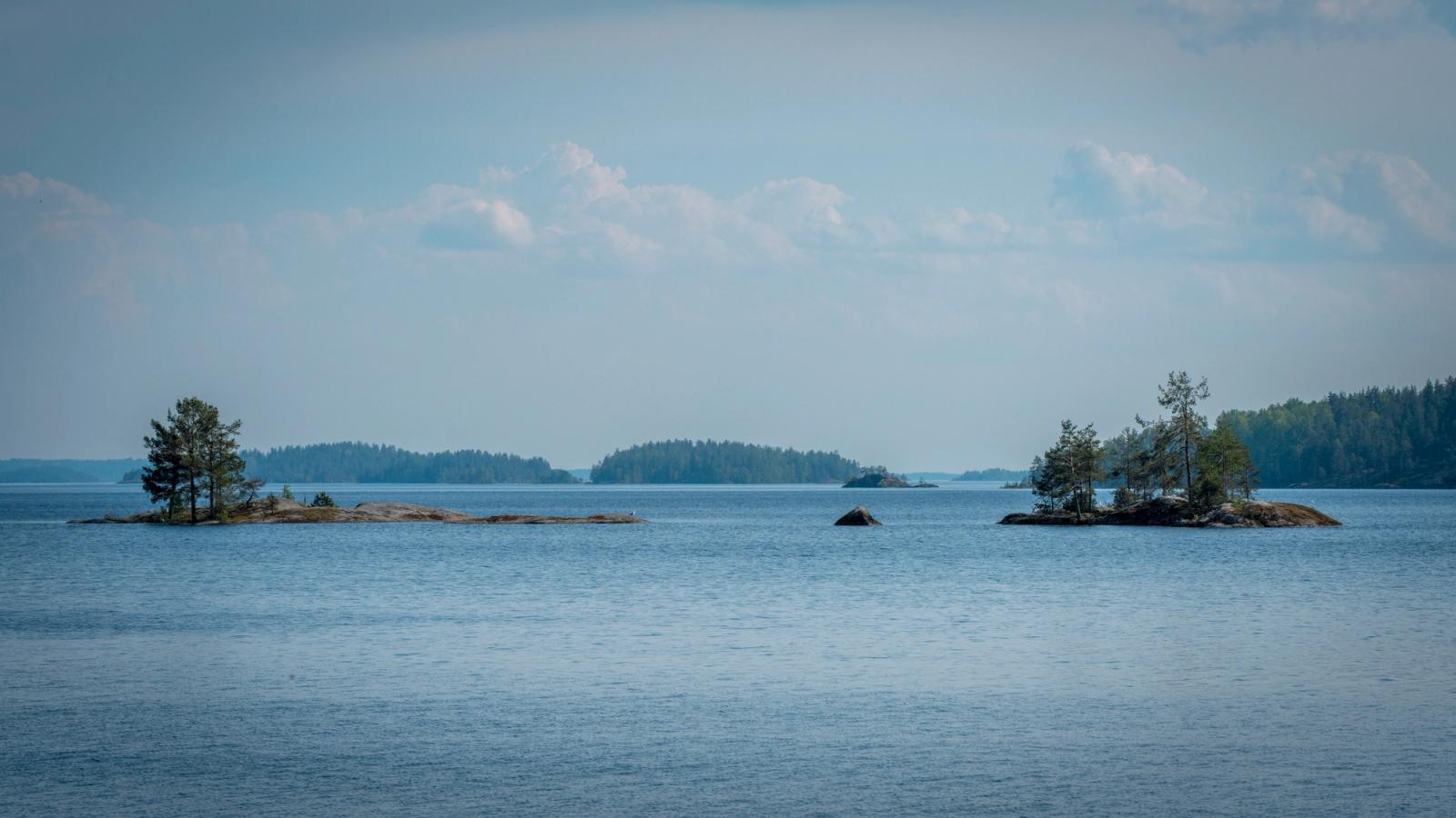 Tranquil view of tree-covered islands on Lake Saimaa reflecting in calm waters under a blue sky