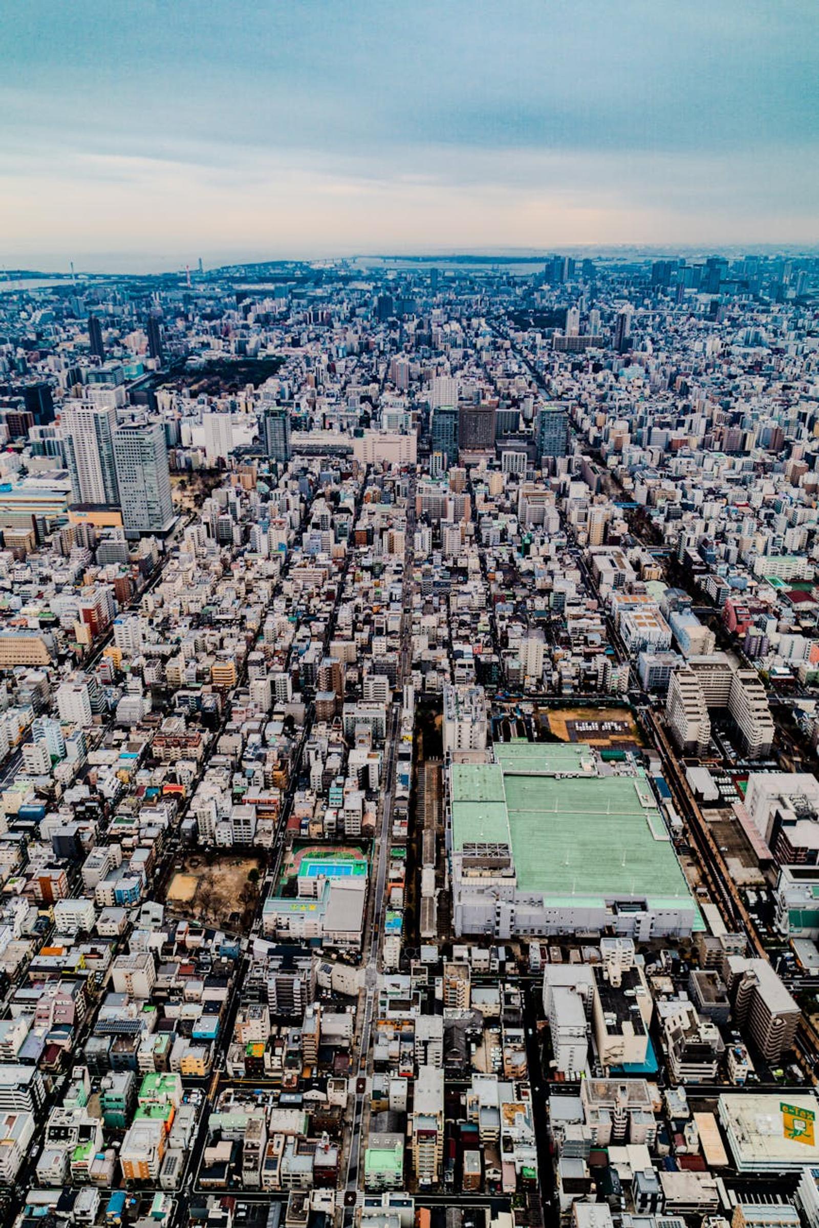 Aerial view of dense city blocks with a green sports field below