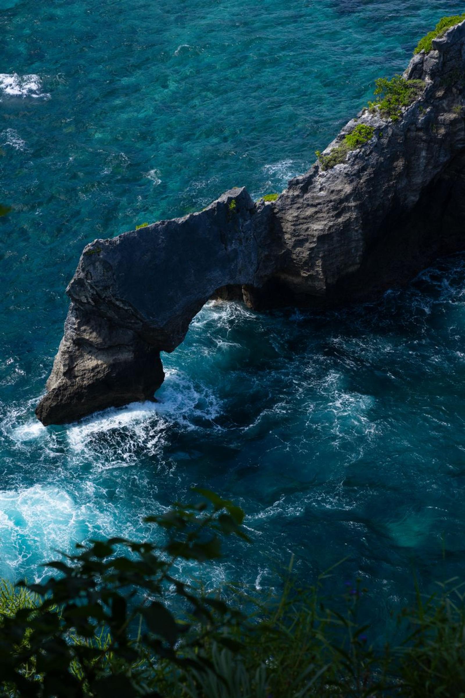 Stunning aerial view of a natural rock arch over turquoise ocean waves