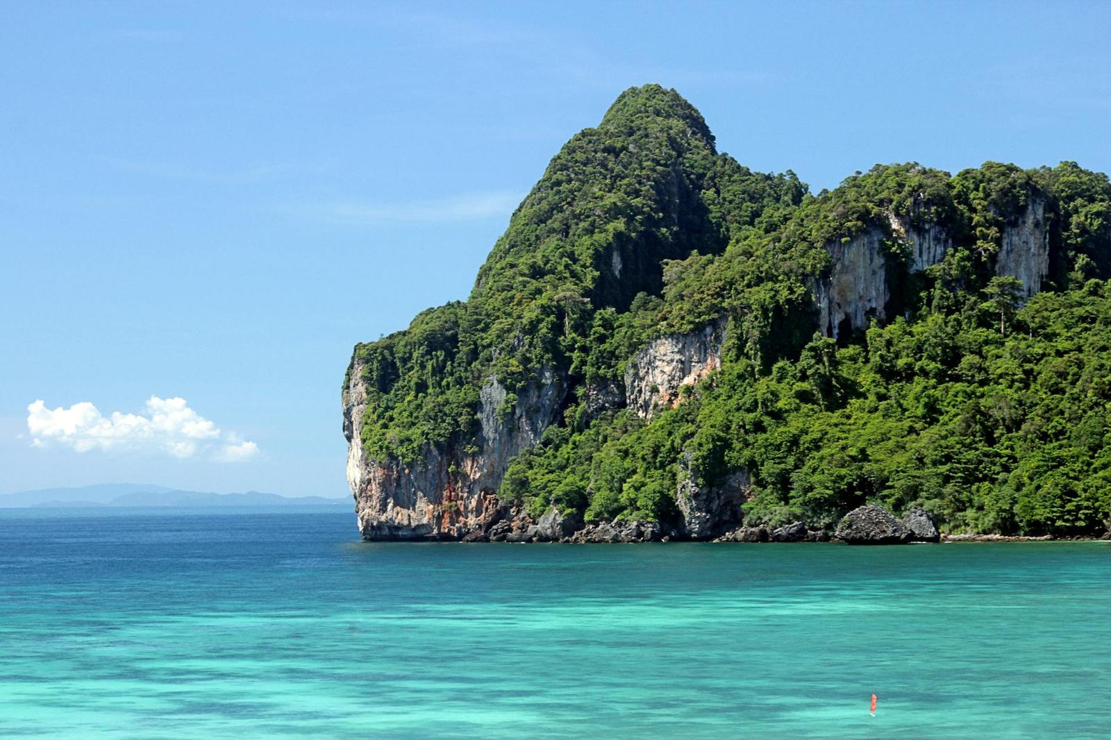 A limestone karst island rising from turquoise water under a clear sky