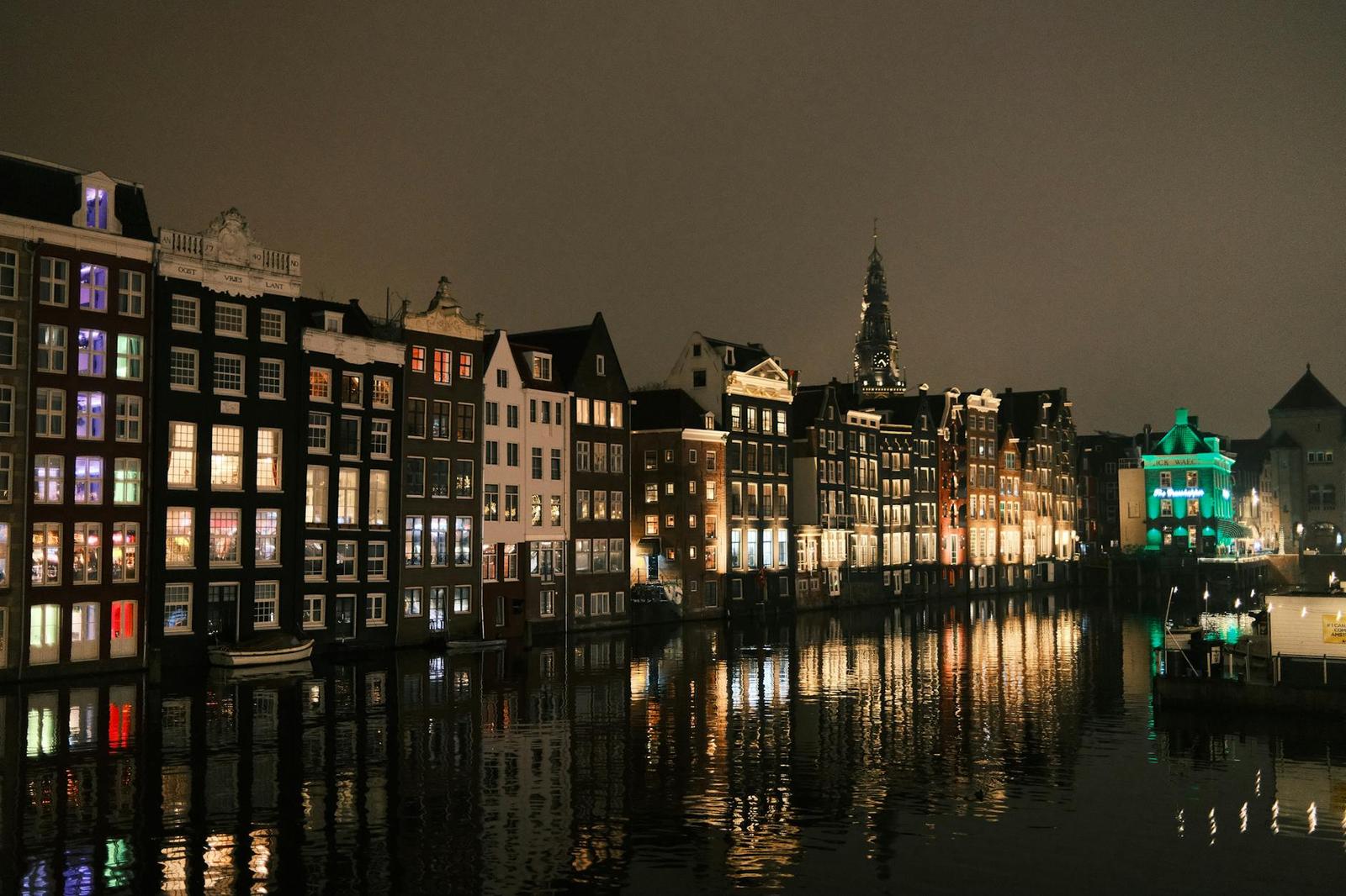 Canal houses reflected in still water lit up at night
